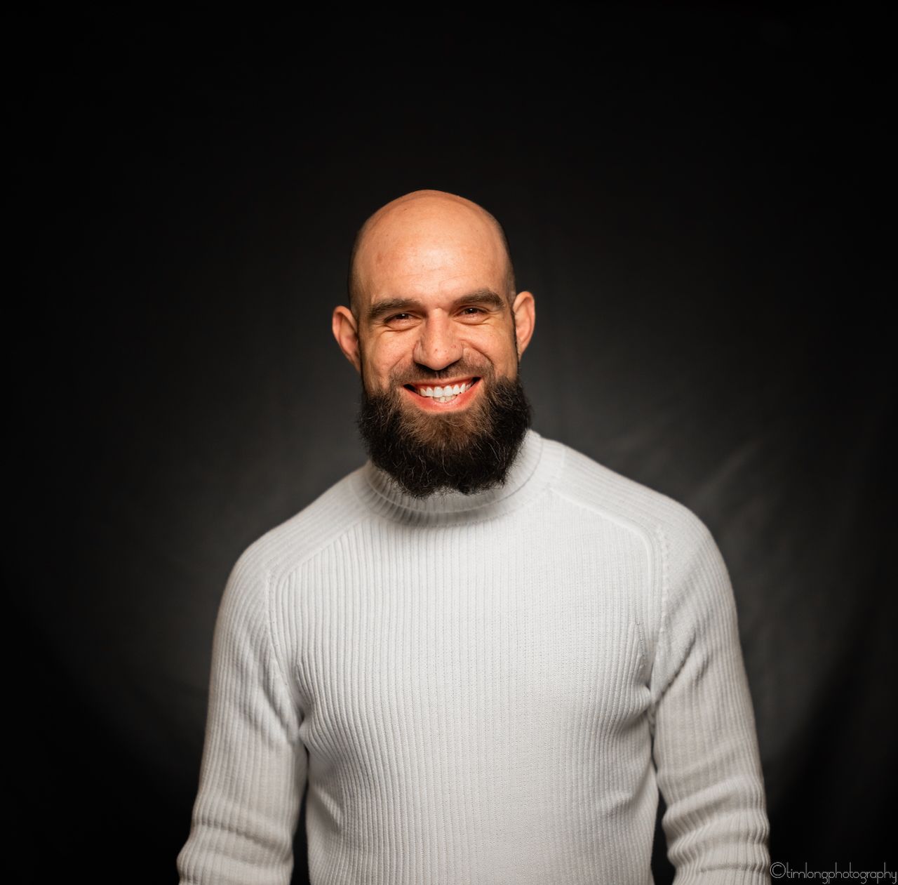 Portrait against dark background wearing white ribbed sweater.