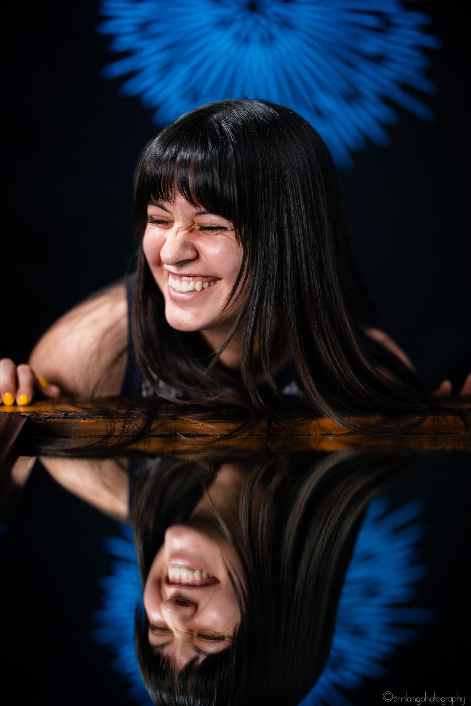 Artistic reflection portrait with blue lighting and dark background.