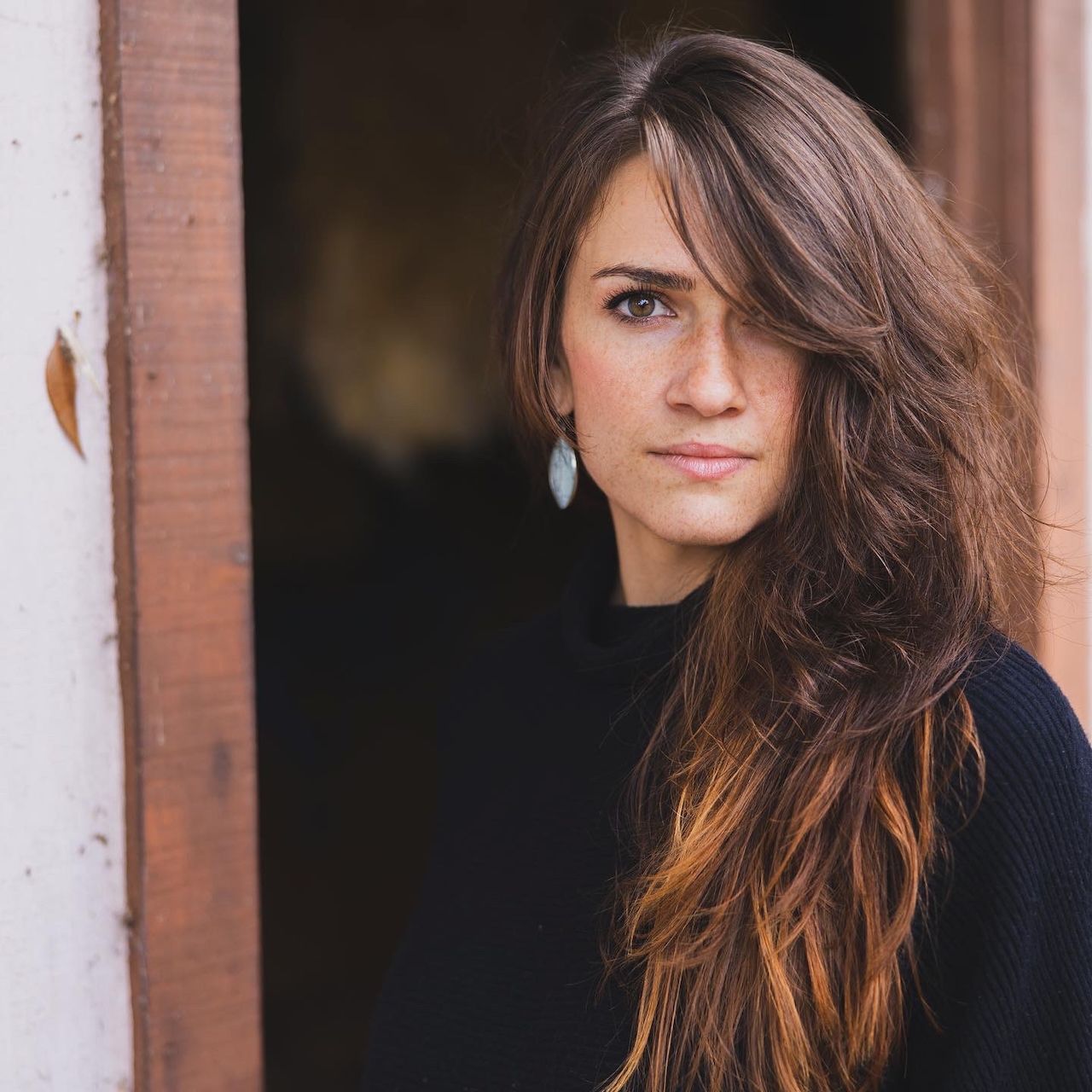 Long brown hair flowing in natural light against white columns.