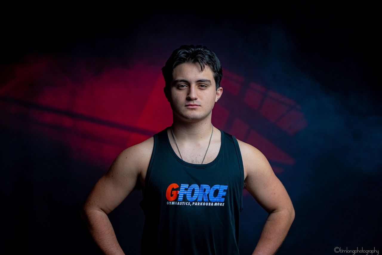 Athletic person in black GForce tank top against dark background with red lighting.