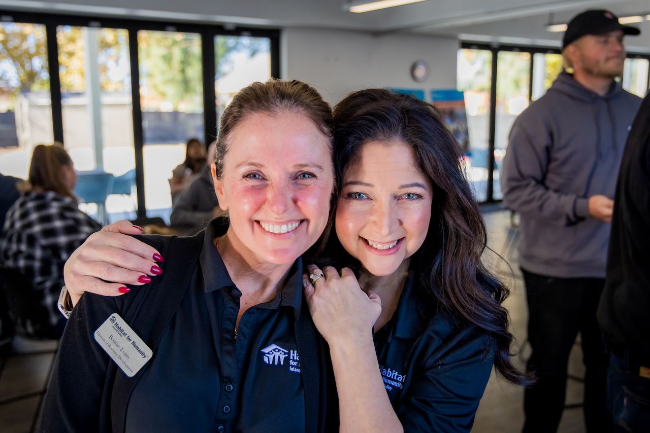 Two staff members in blue uniforms smiling together at company event.