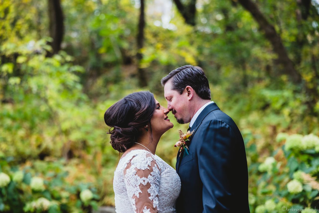 Romantic wedding photo of couple embracing in a lush green garden.