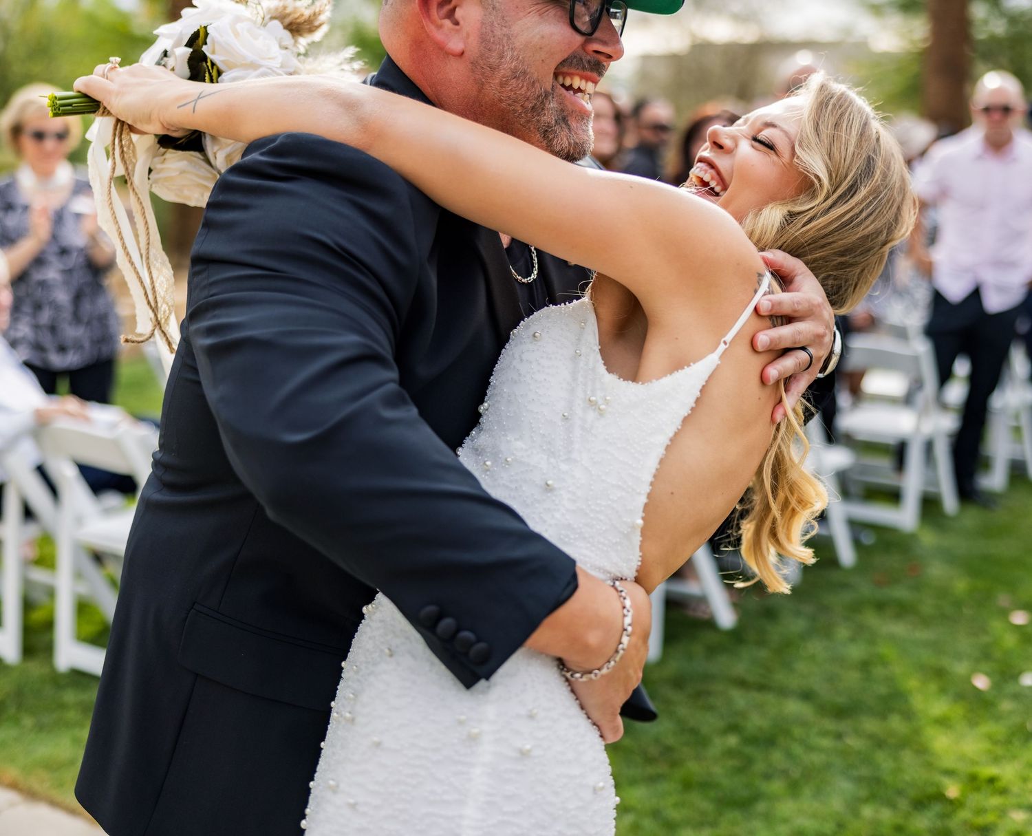 Wedding couple dancing and laughing together during their outdoor reception celebration.