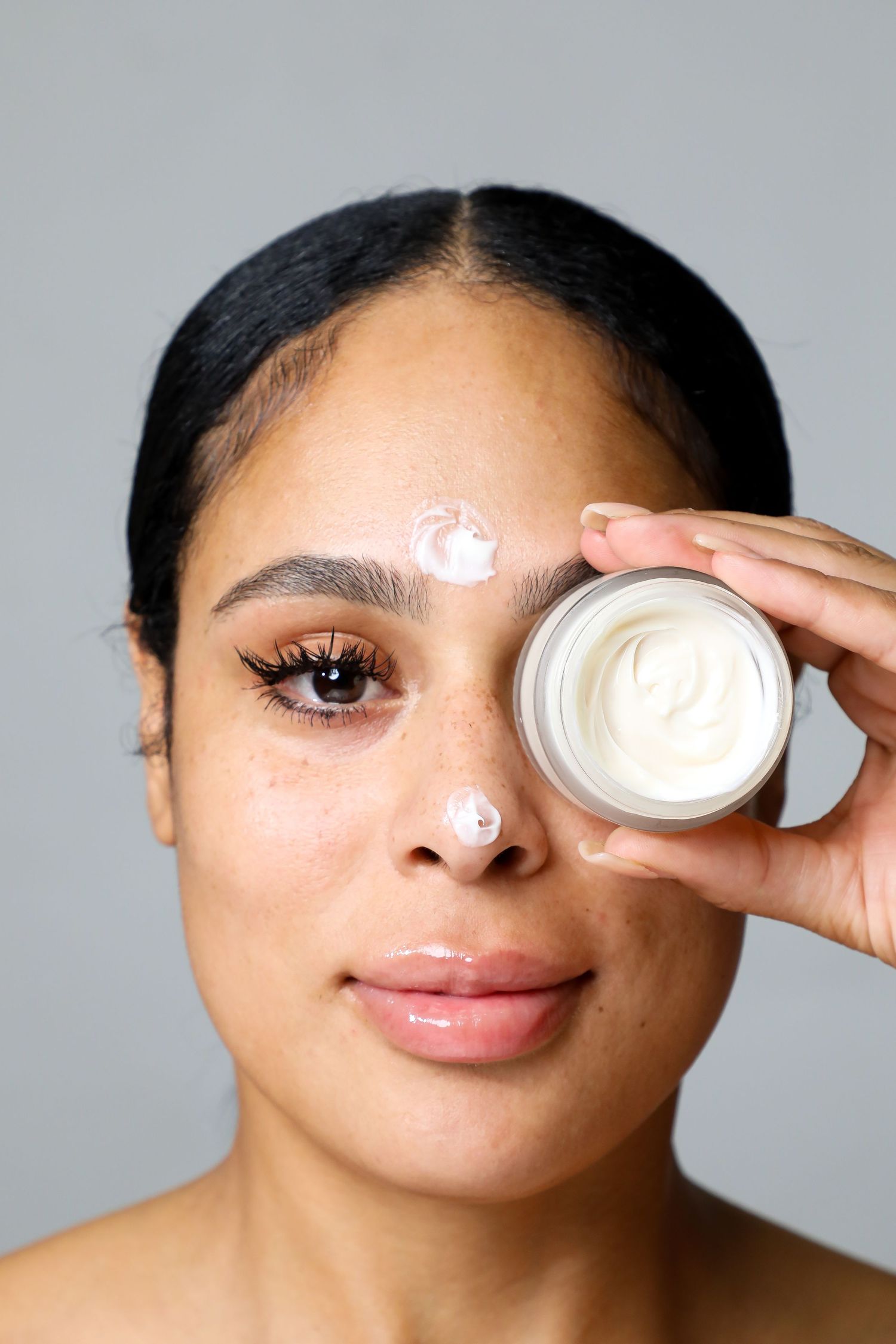 Beauty product demonstration showing cream application around eye area.