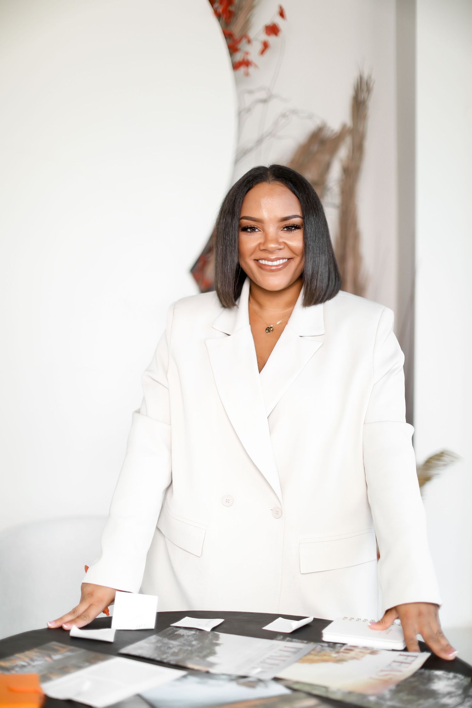 Business portrait session in white blazer at desk with modern minimalist setting.