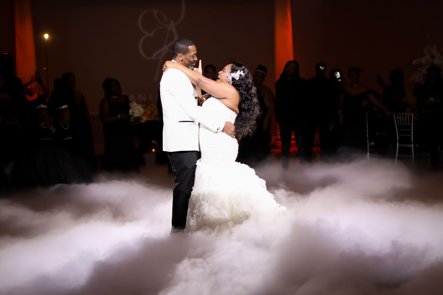 Couple dancing on a misty dance floor lit with dramatic lighting.