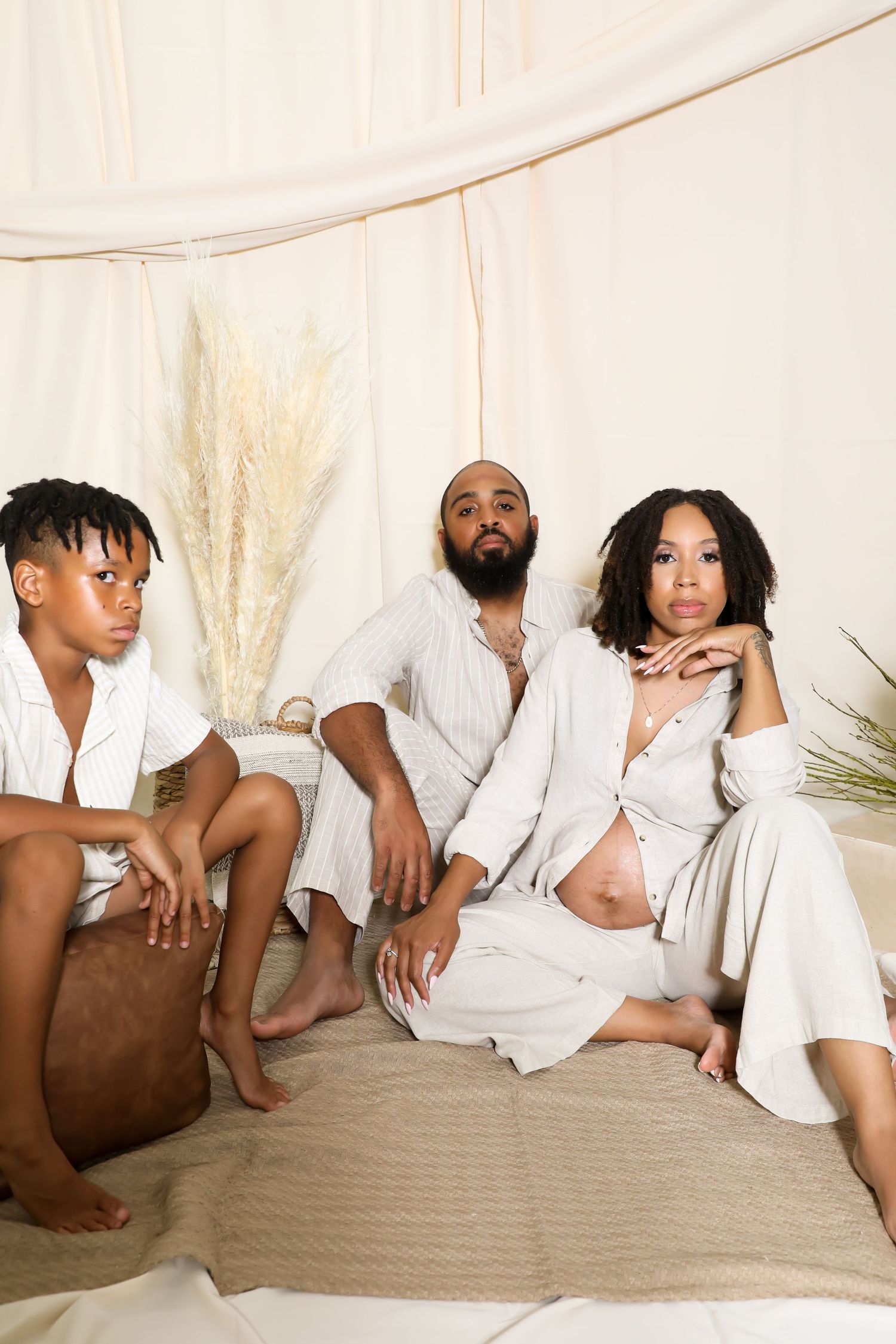 Group lounging in white clothing against neutral backdrop in artistic arrangement.