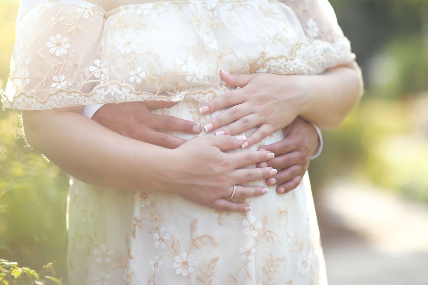 Close-up shots of hands tenderly cradling a pregnant belly in soft natural lighting.