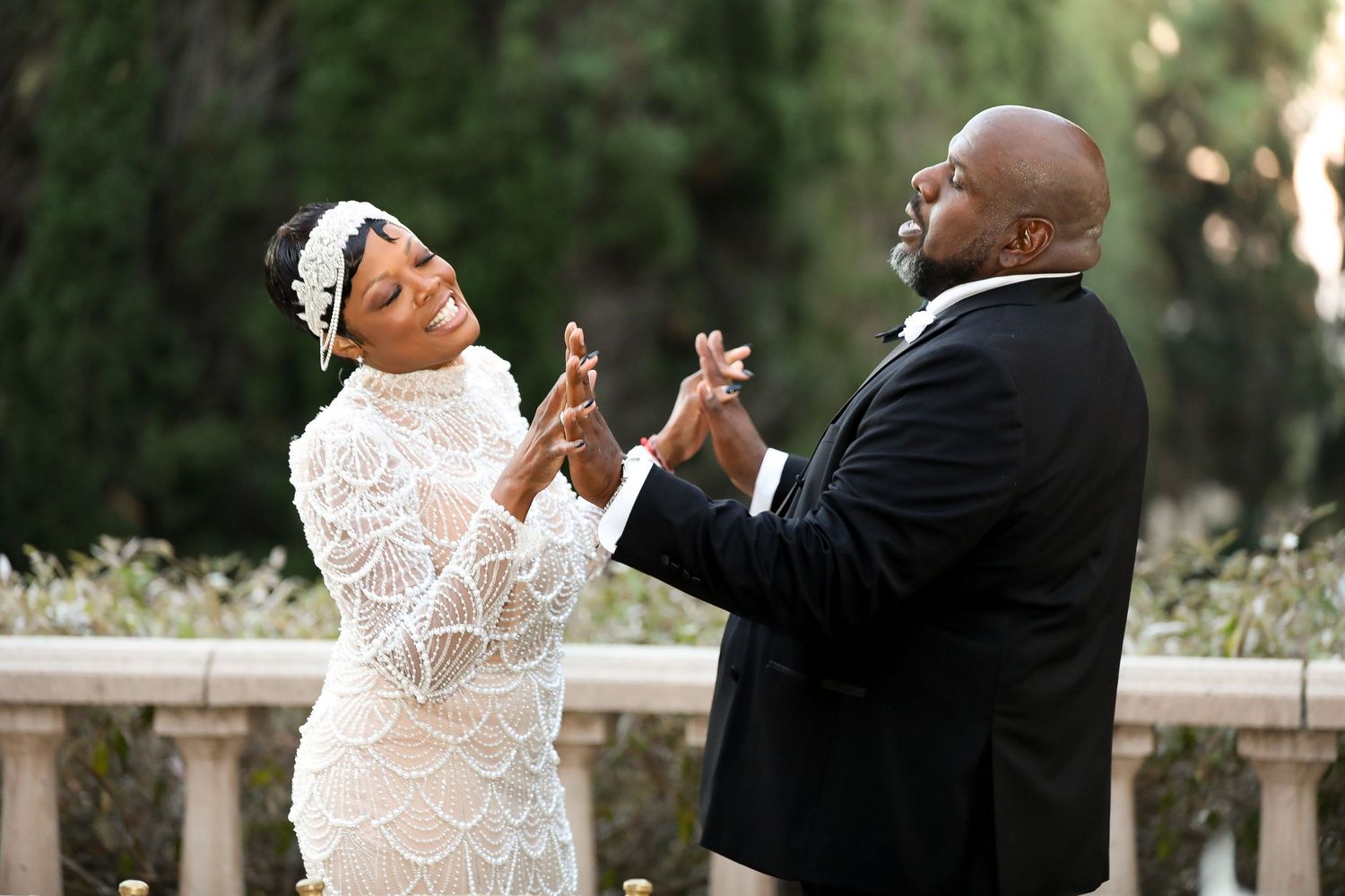 Wedding couple shares joyful moment while holding champagne glasses outdoors.