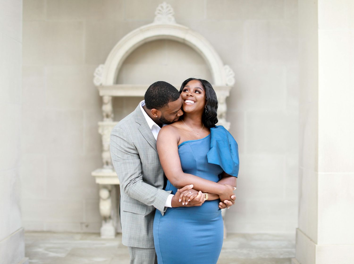 Intimate couple photography session against elegant white architectural backdrop.
