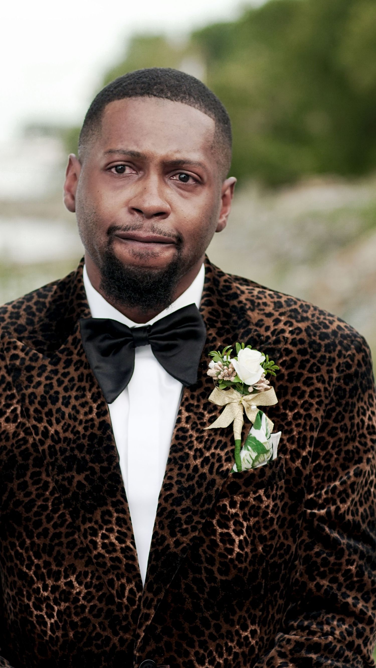 Groom wearing a leopard print tuxedo jacket with white boutonniere.