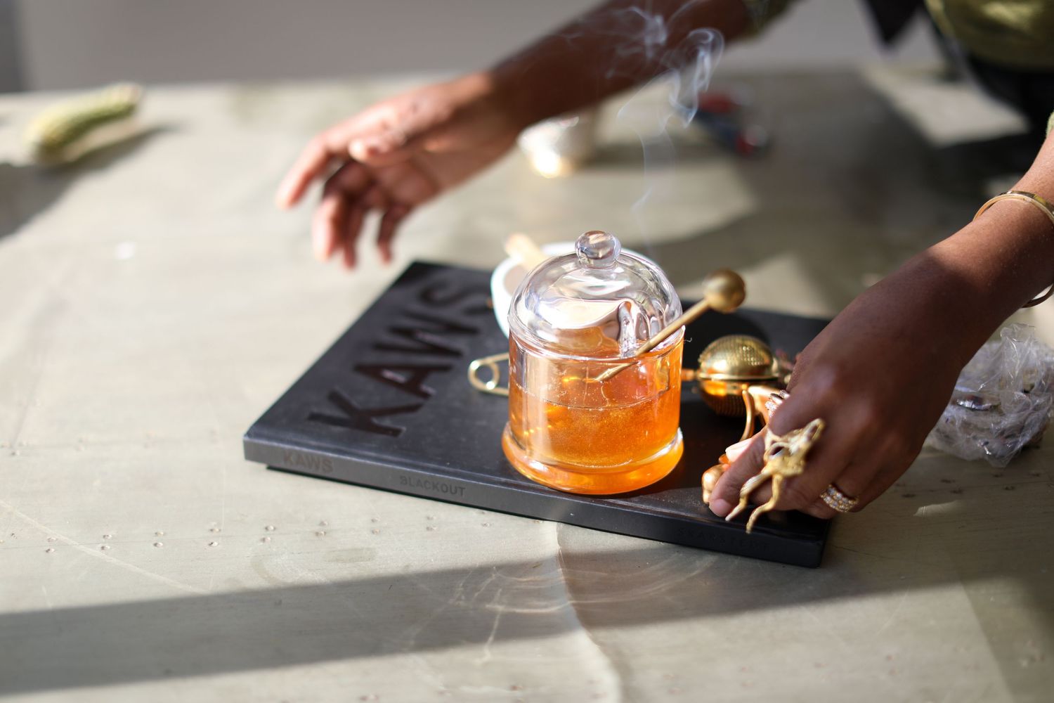 Hands reaching for cocktail glasses on a dark surface with dramatic lighting.