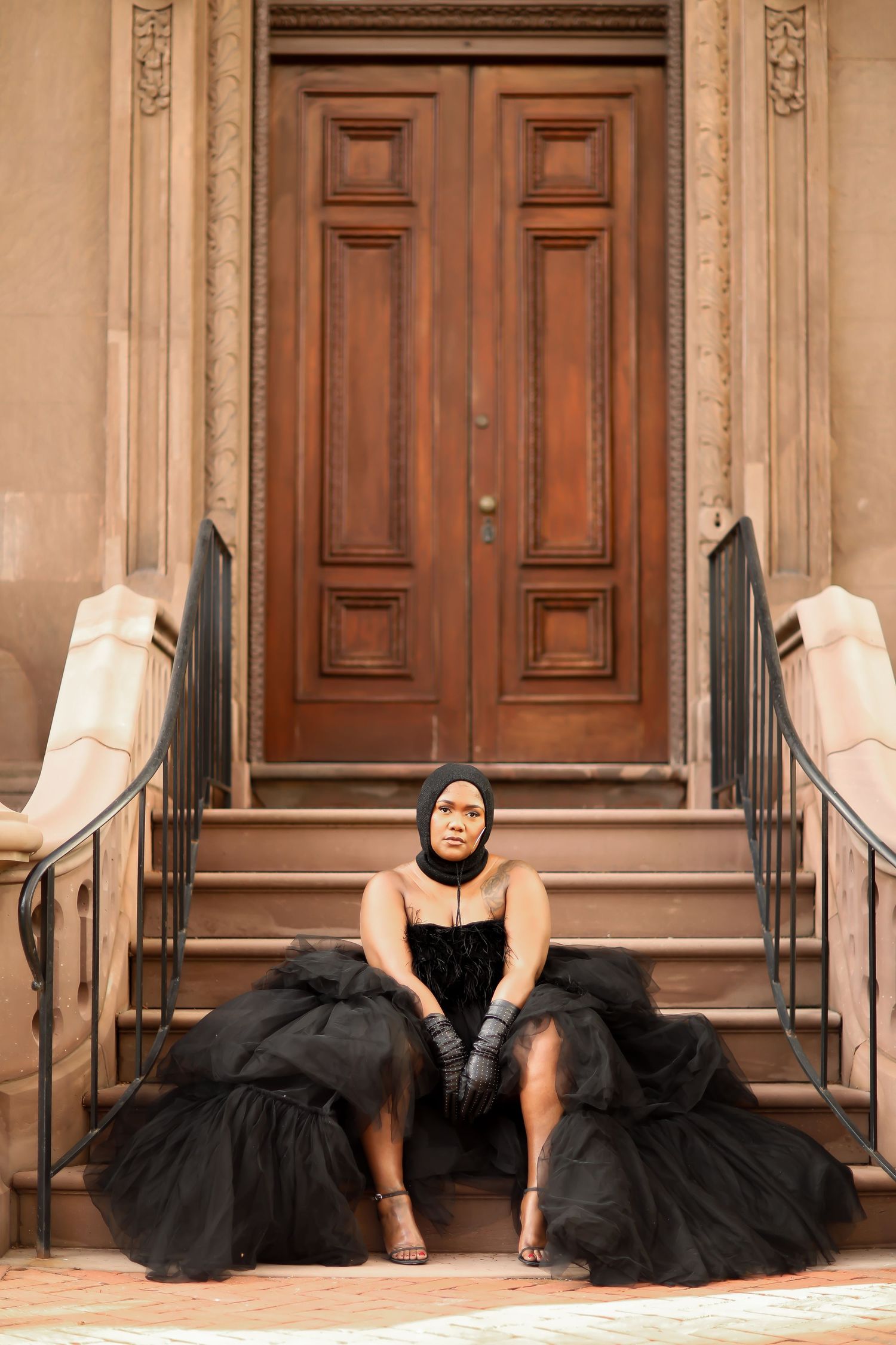 Two models in flowing black dresses lie dramatically on stone steps in an artistic fashion pose.