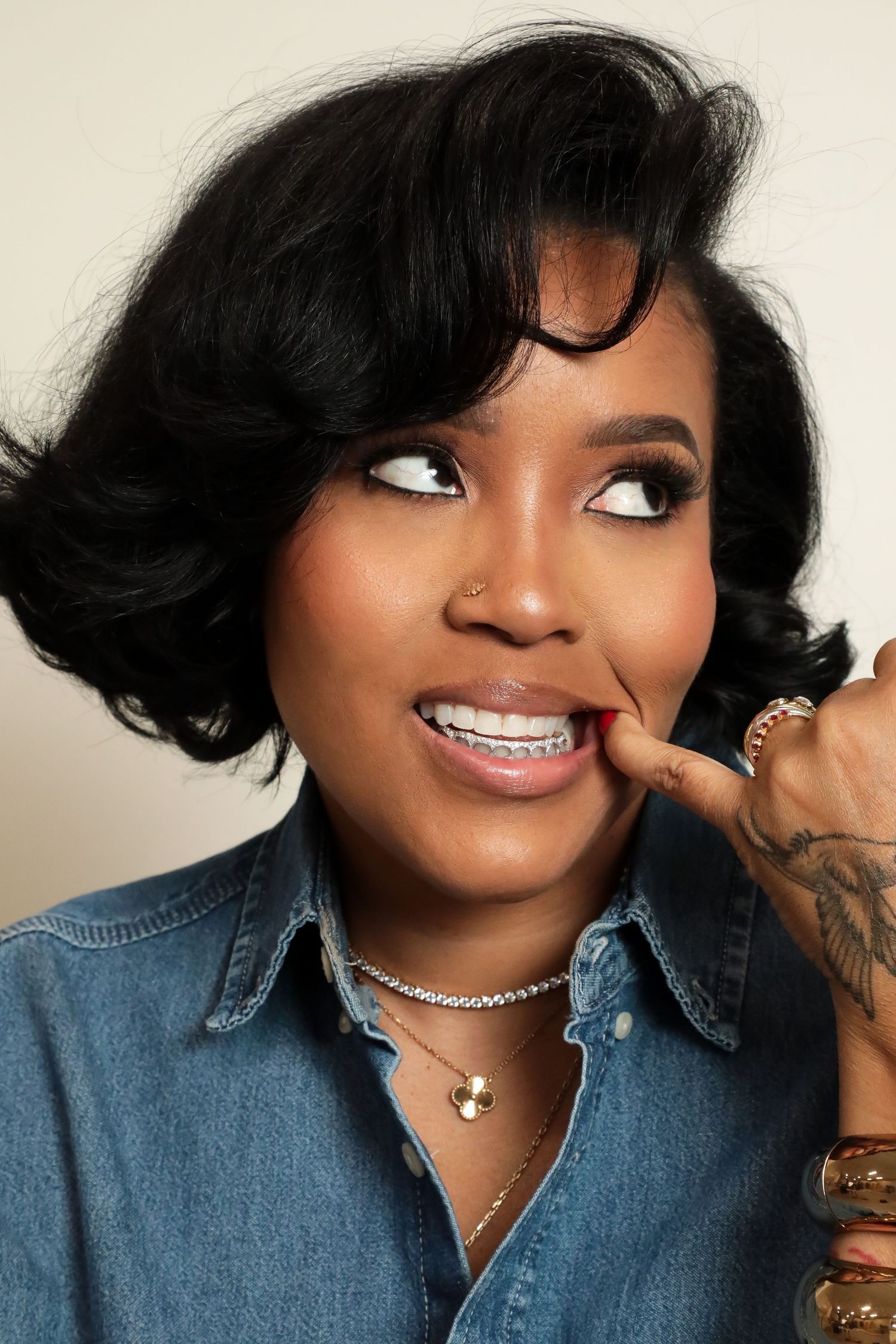A series of headshots showing someone smiling and posing in a denim top with black hair and jewelry.