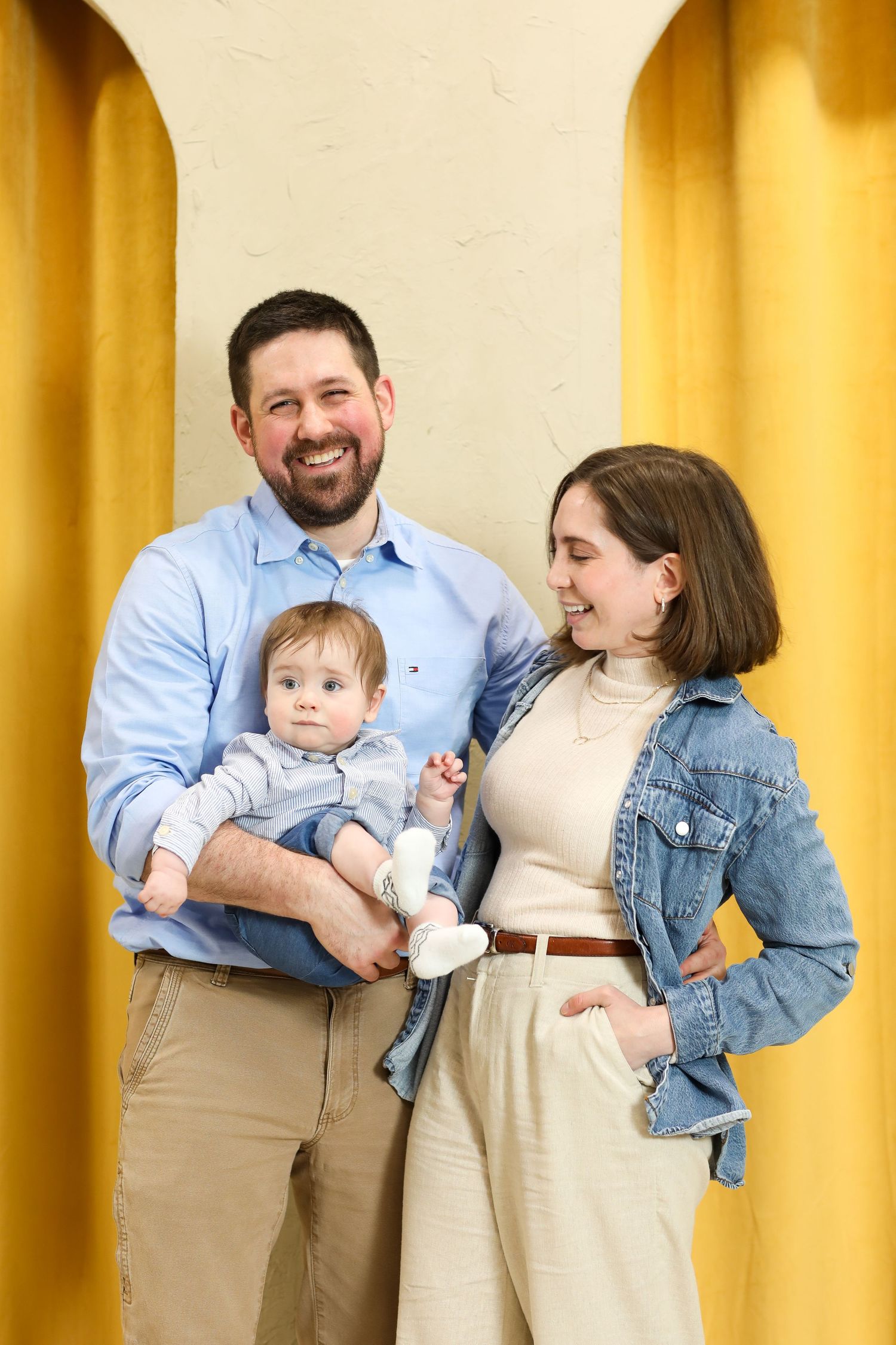 Family posing together against yellow backdrop in casual matching outfits.