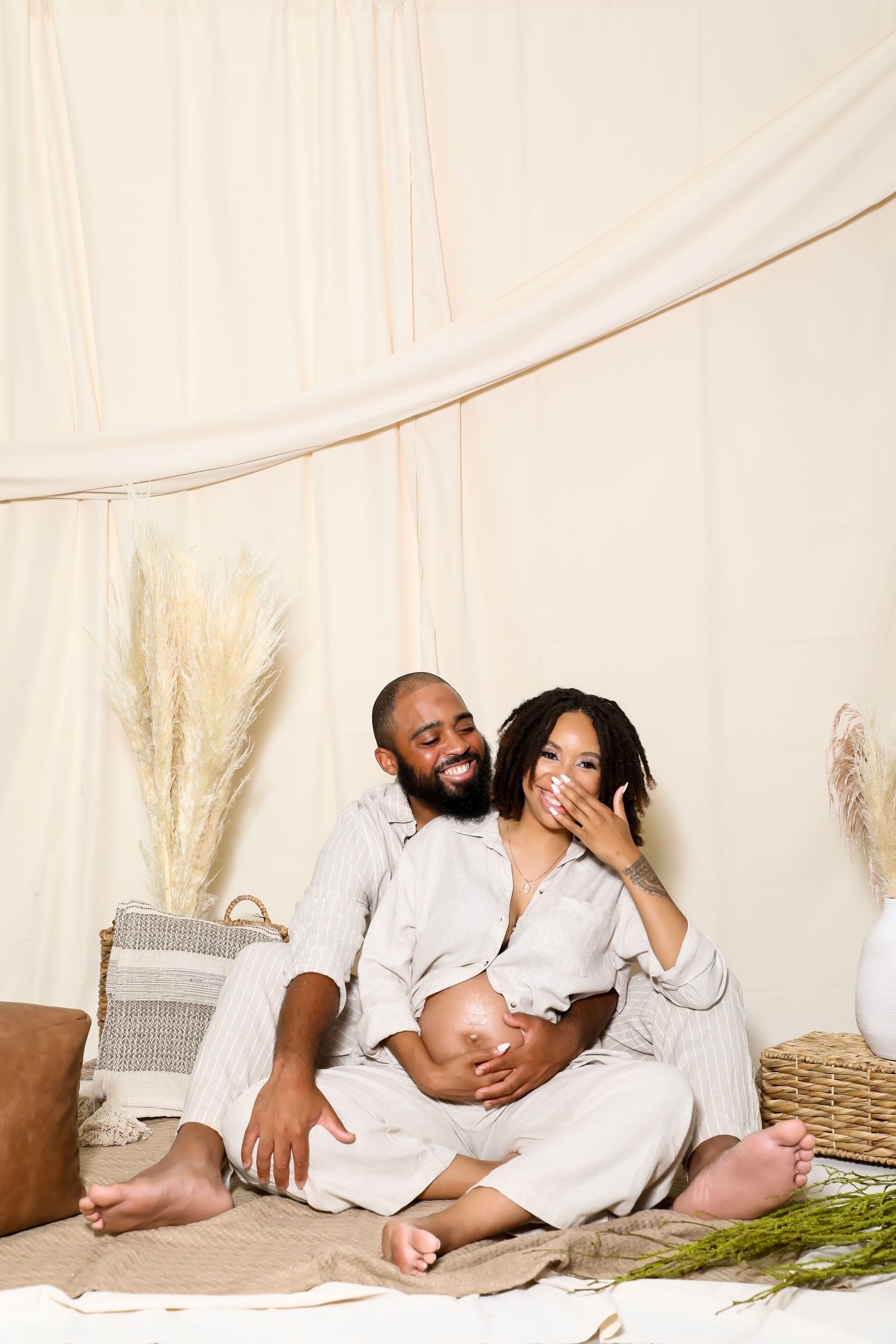 Couple in white relaxing together on floor with pampas grass decoration.