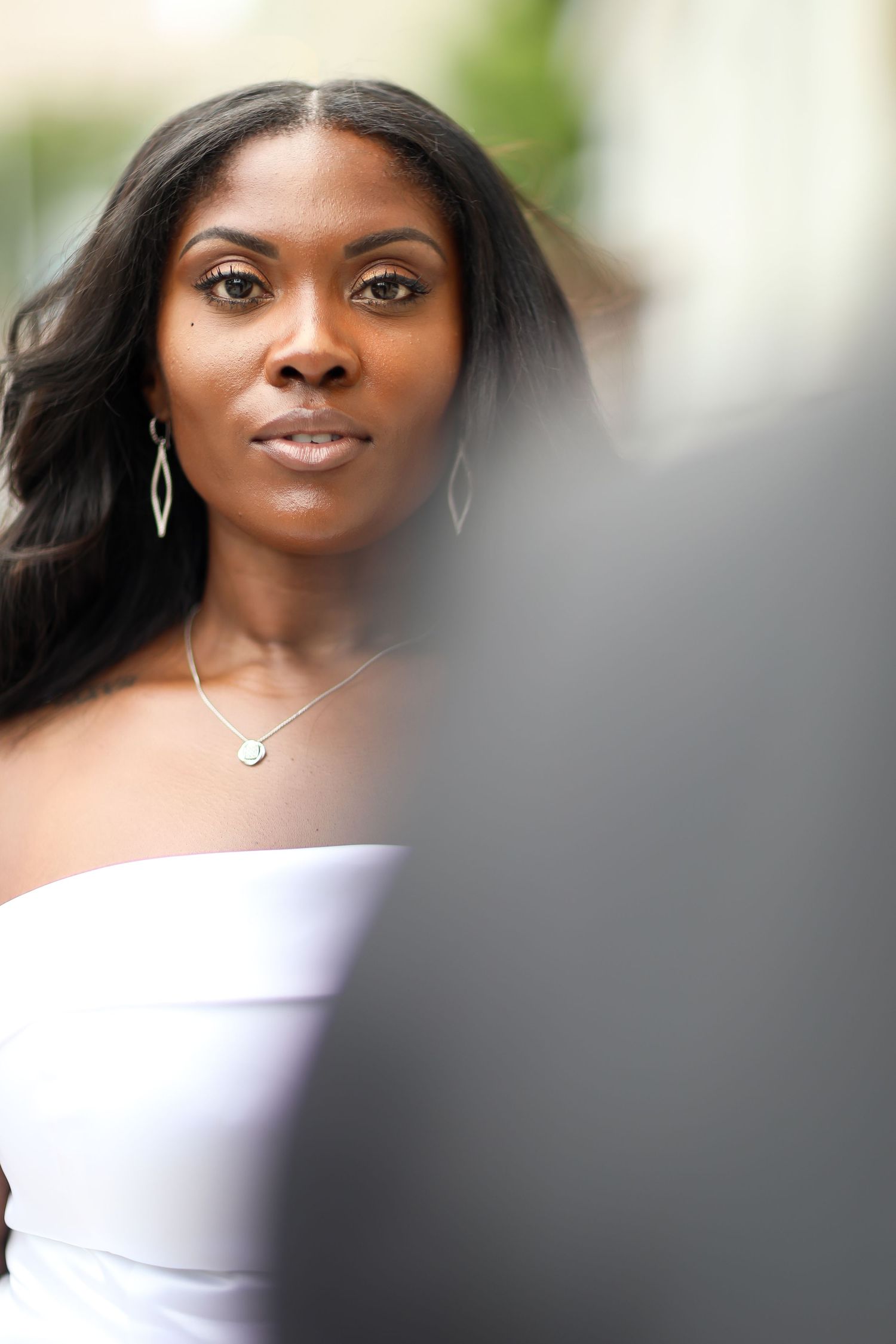 Close-up portrait showing elegant bridal jewelry and white dress details.