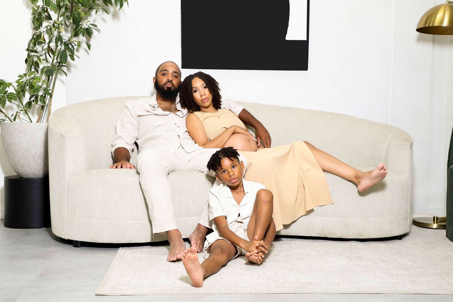 Modern maternity photo session featuring couple relaxing on white furniture.
