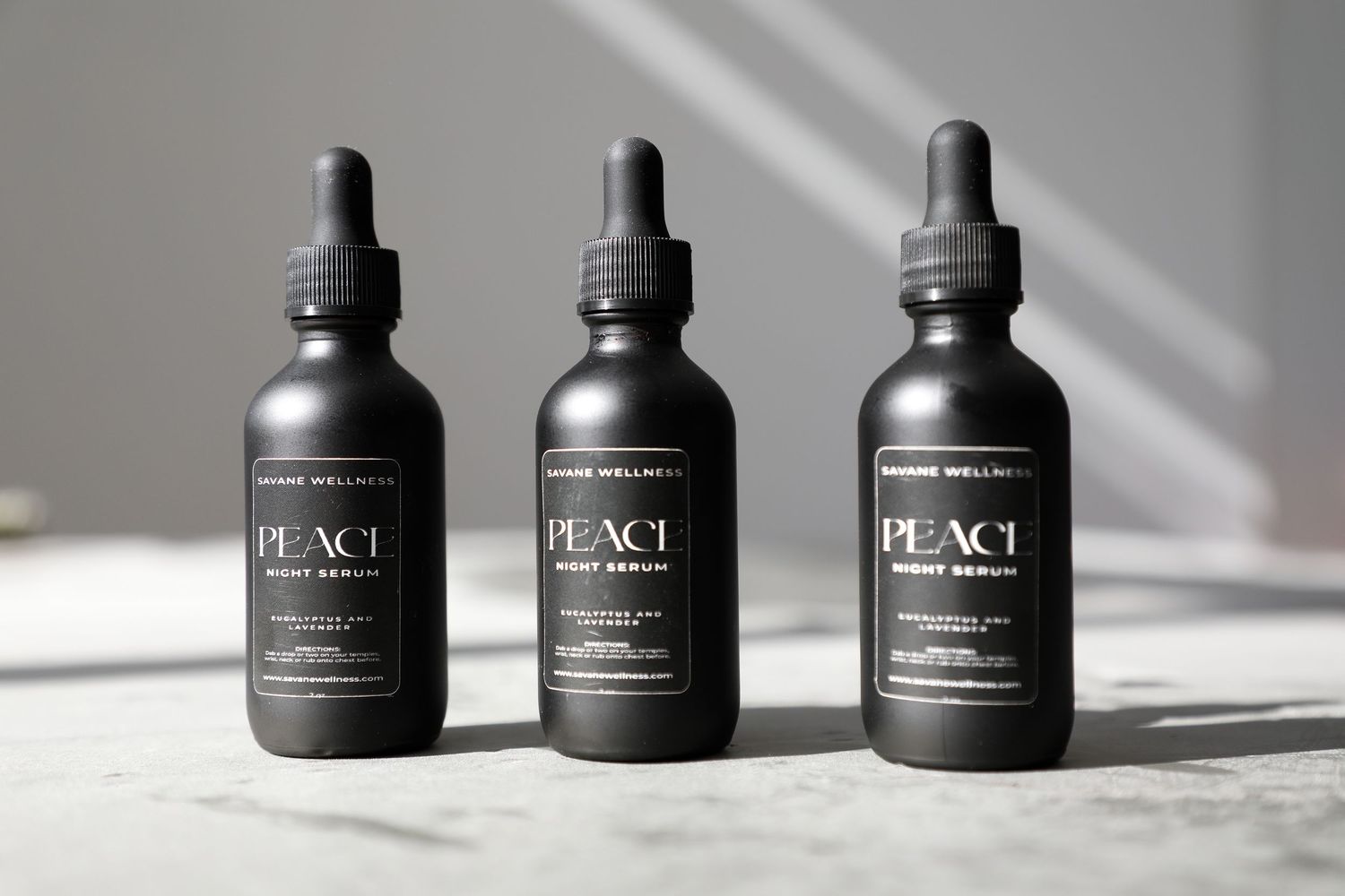 Row of black Peace branded cosmetic bottles arranged artistically with shadows.