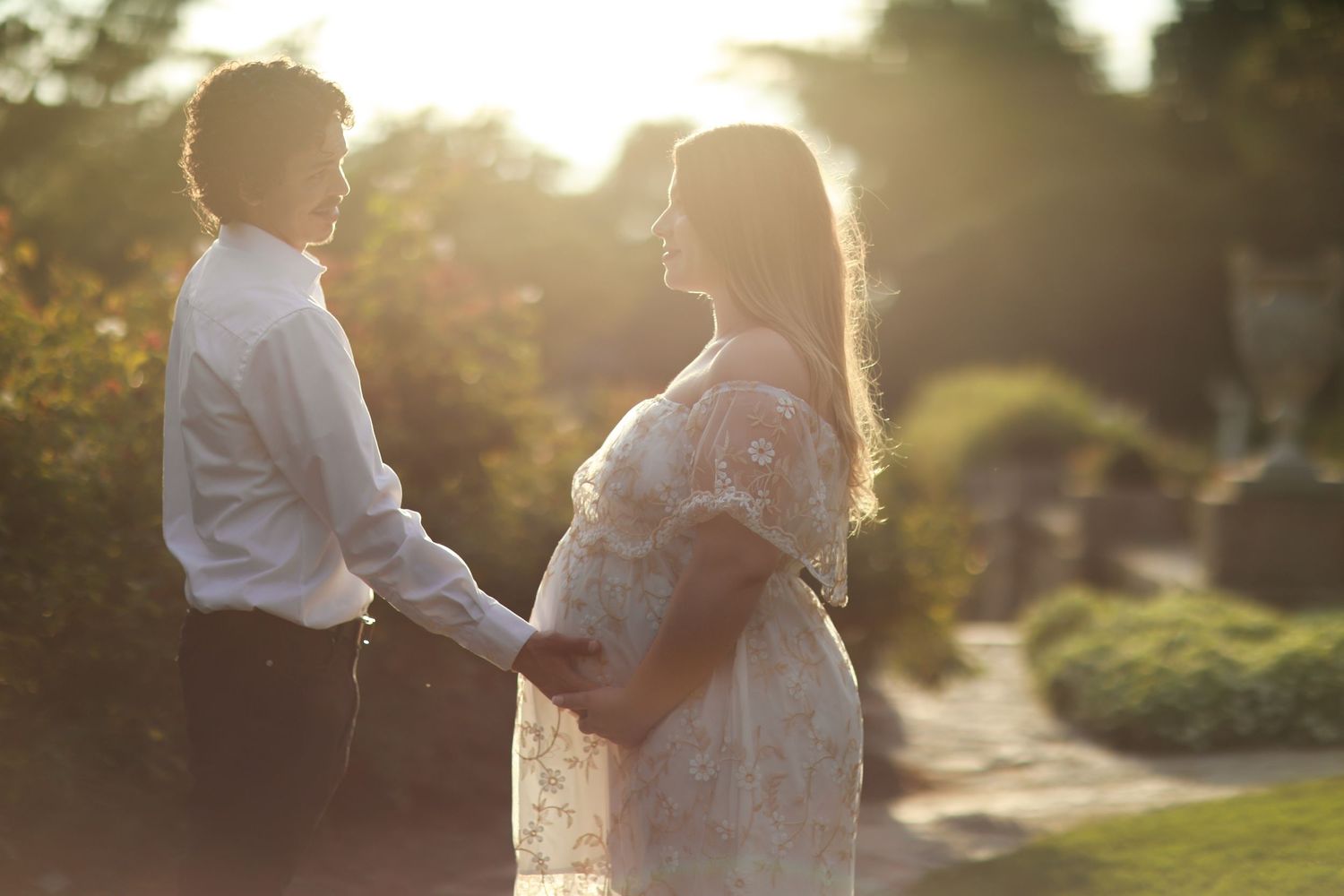 Backlit couple embracing during golden hour outdoor photo session.