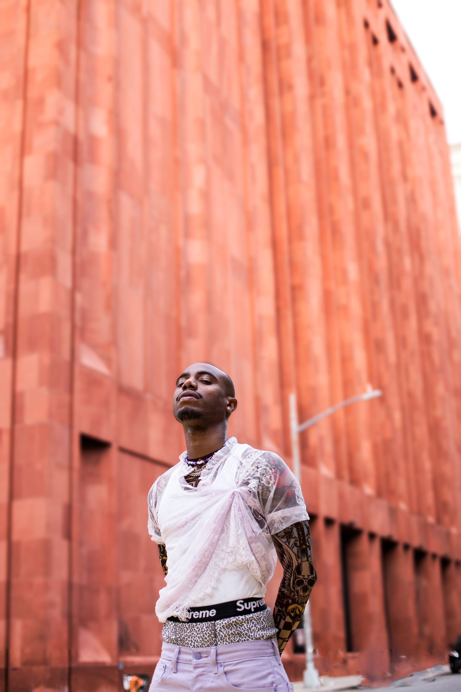 Fashion portraits against a textured orange wall in urban setting.