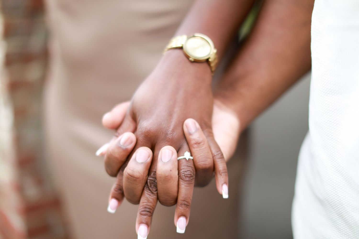 Close-up of hands showing diamond engagement ring and matching wedding bands.