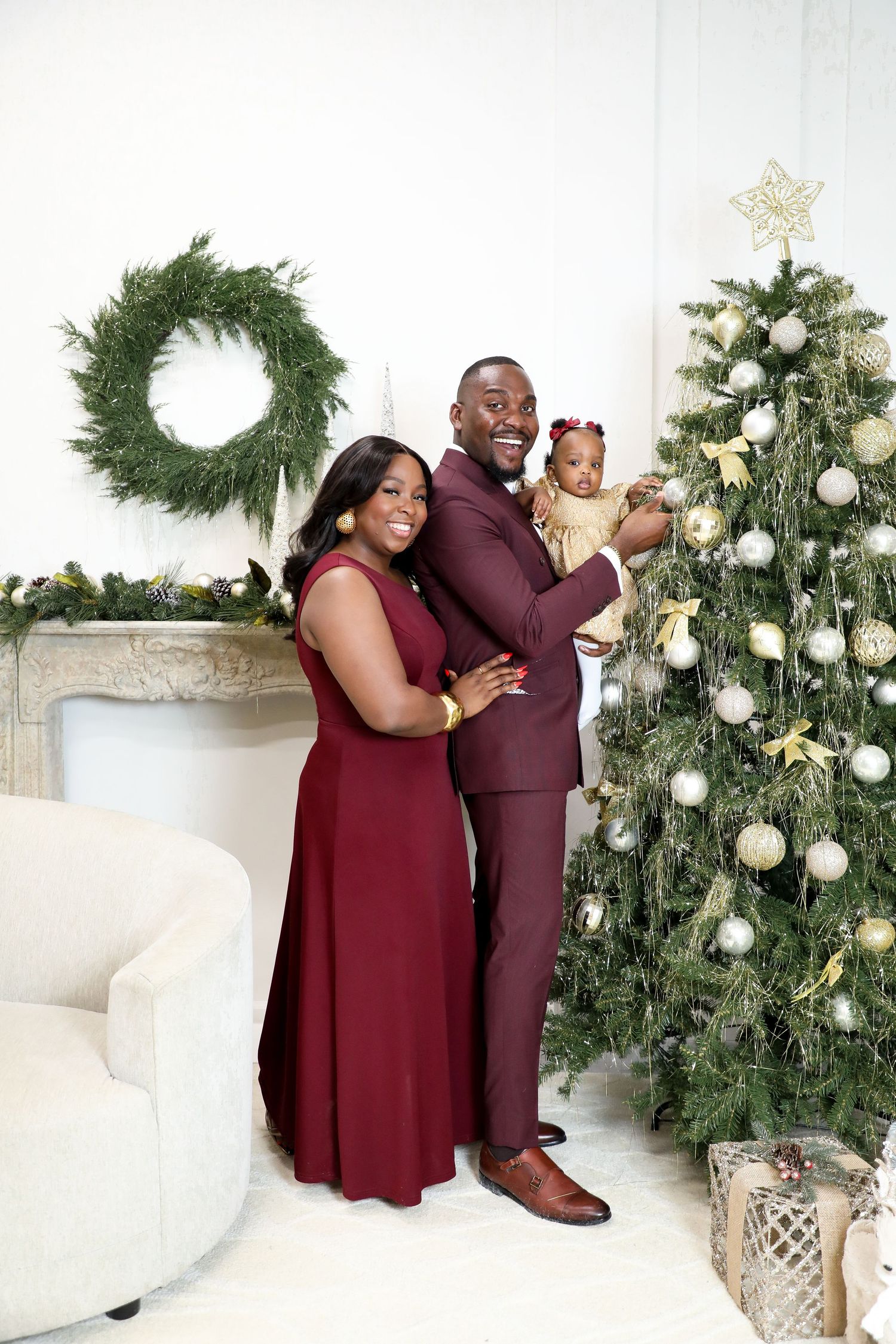 Christmas themed family photoshoot with decorated evergreen trees and white ornaments.