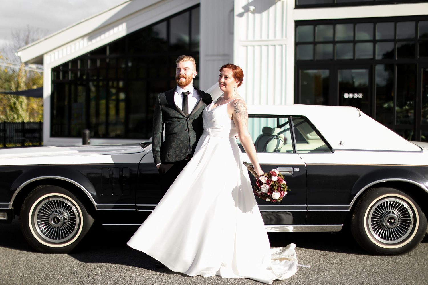 Classic black vintage car parked outside with white wedding attire visible.