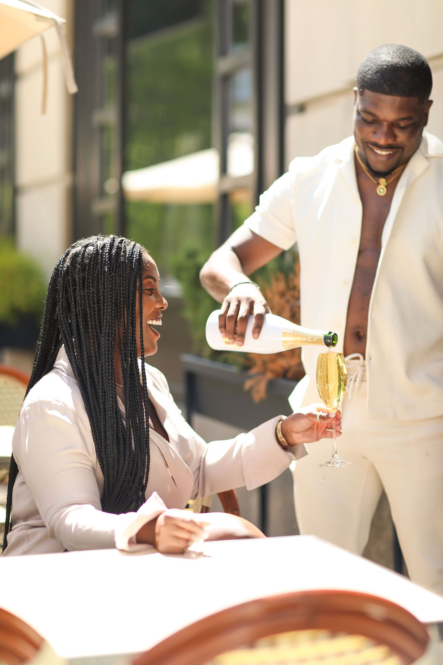 Group enjoying drinks and conversation at an outdoor table in elegant attire.