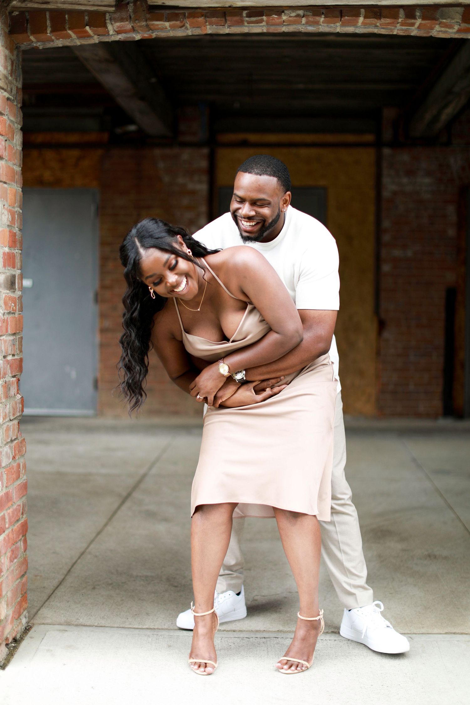 Romantic couple shoot in industrial setting with exposed brick walls and casual attire.