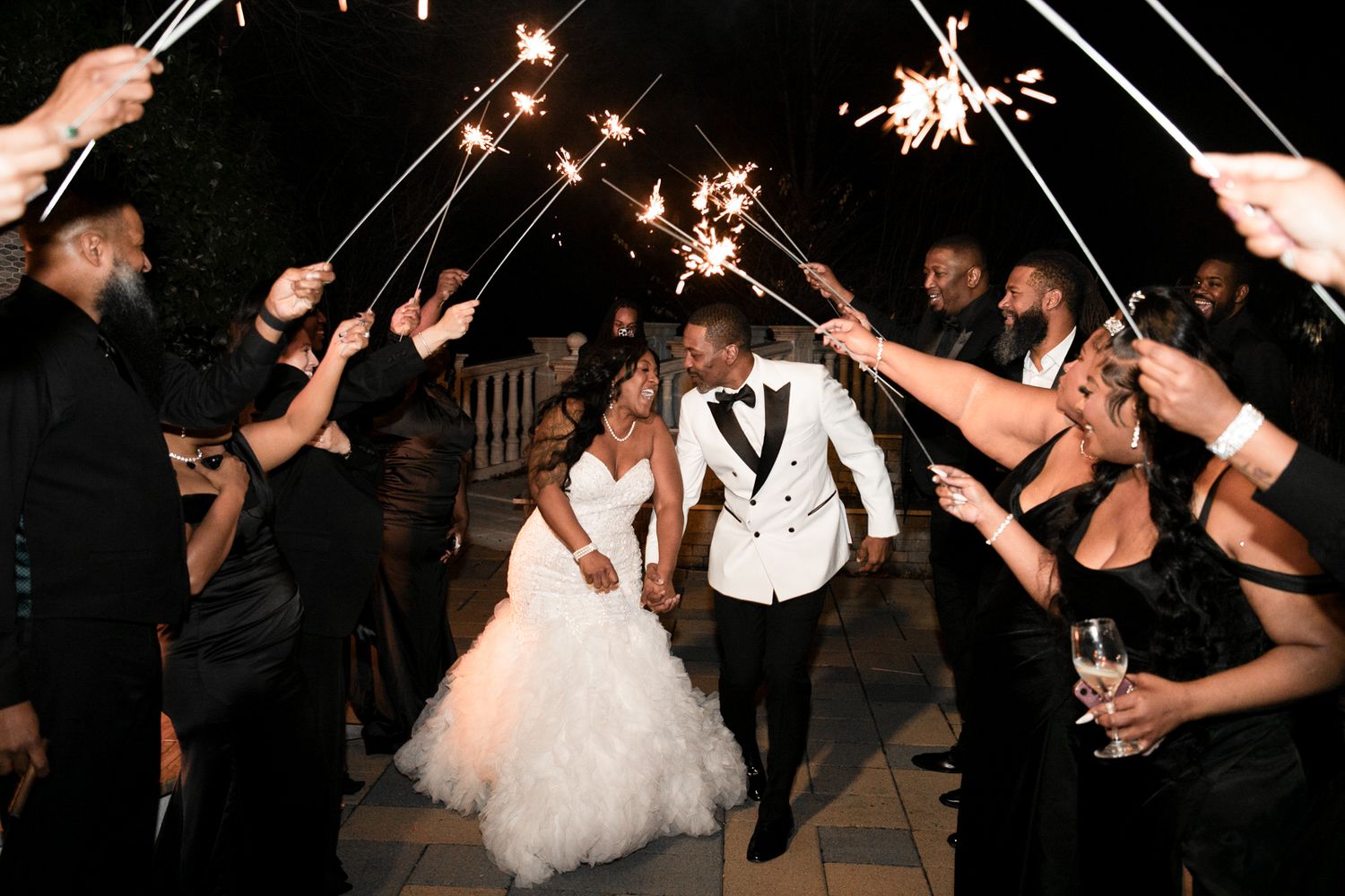 Wedding party guests wave sparklers during an evening celebration.