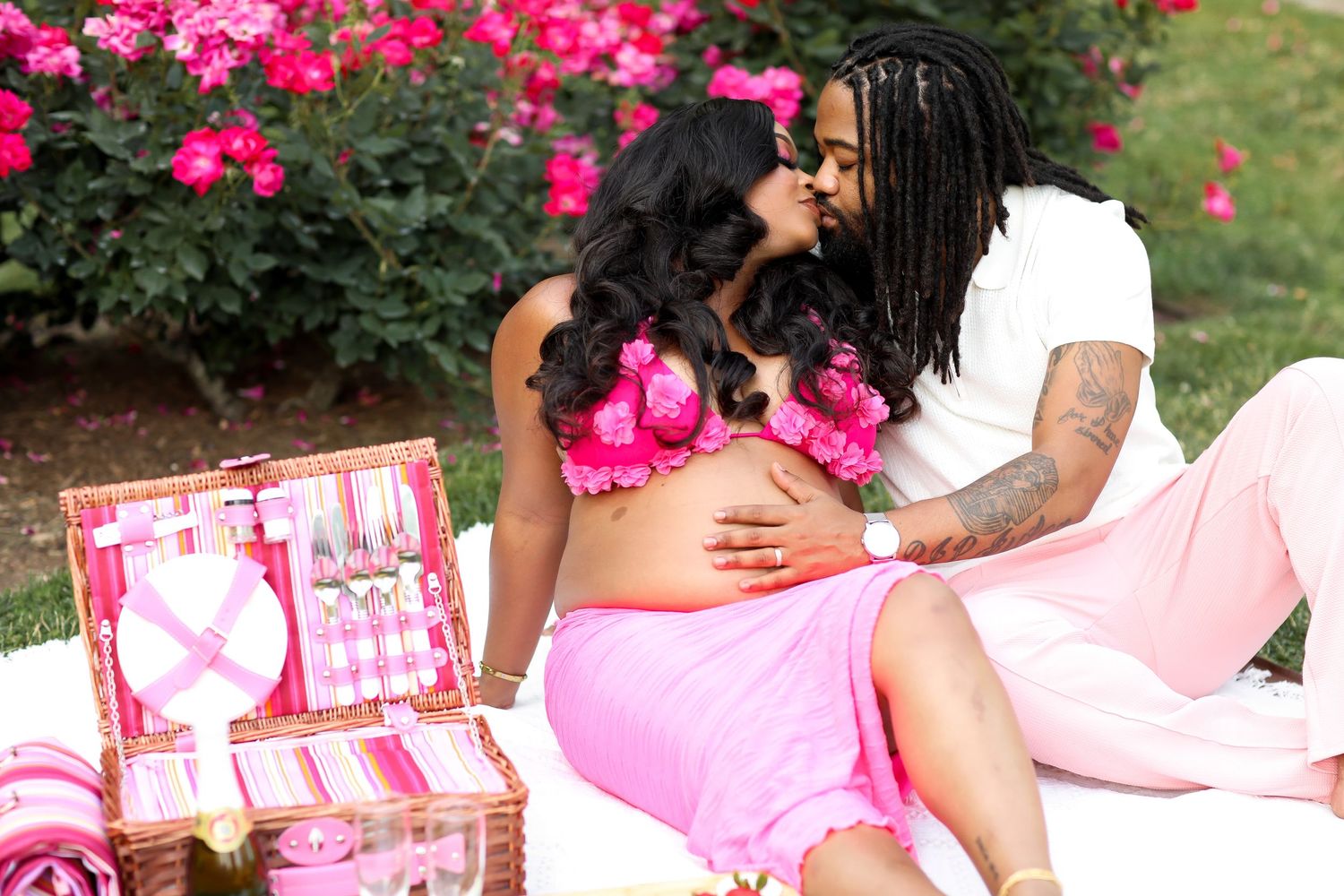 Romantic garden picnic scene with pink roses and blanket spread on grass.