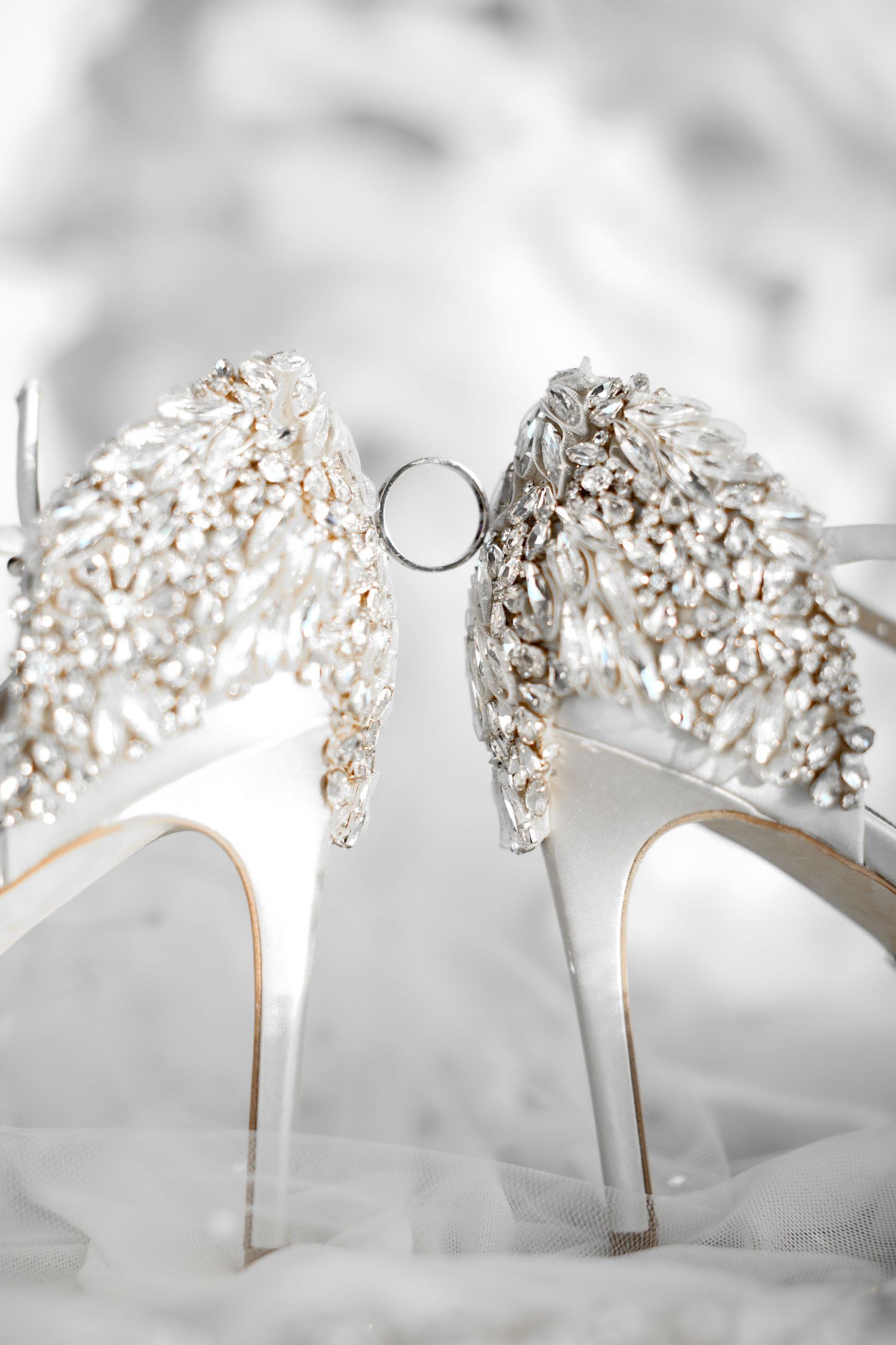 Crystal-embellished white bridal heels arranged in a row.