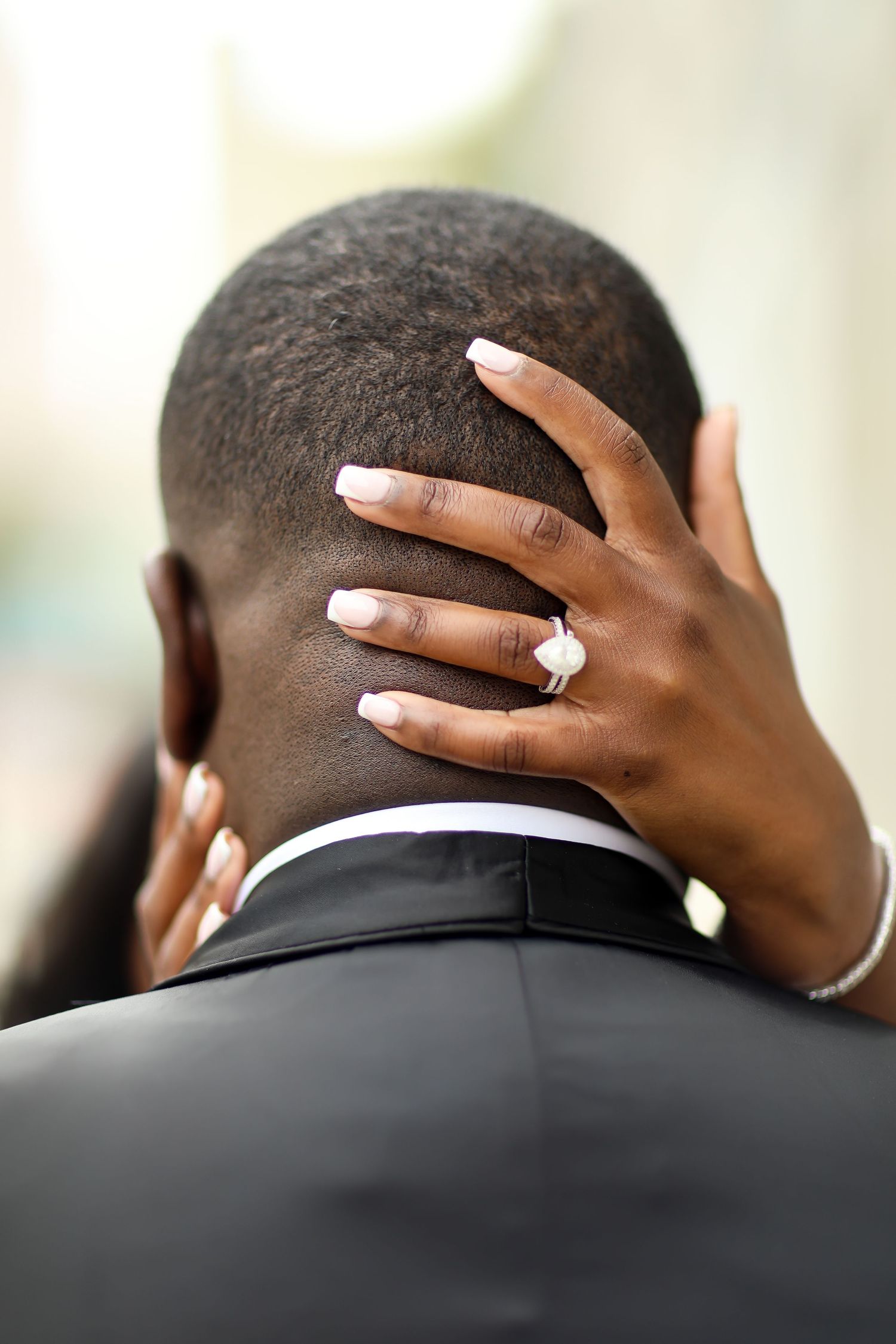 Close-up detail shots of hands wearing wedding rings against a black suit jacket.