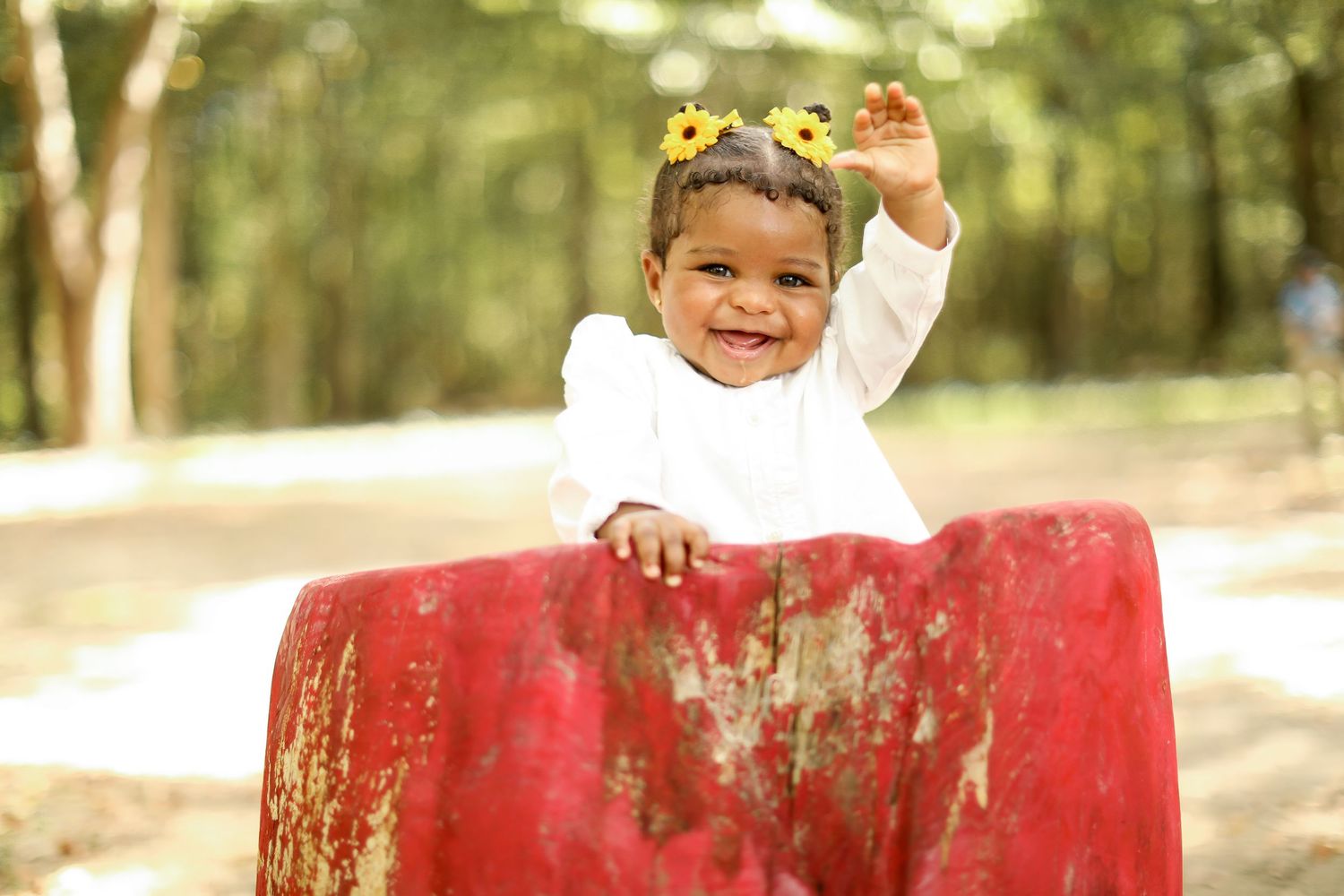 Outdoor portrait session featuring red bench and natural sunlit background.