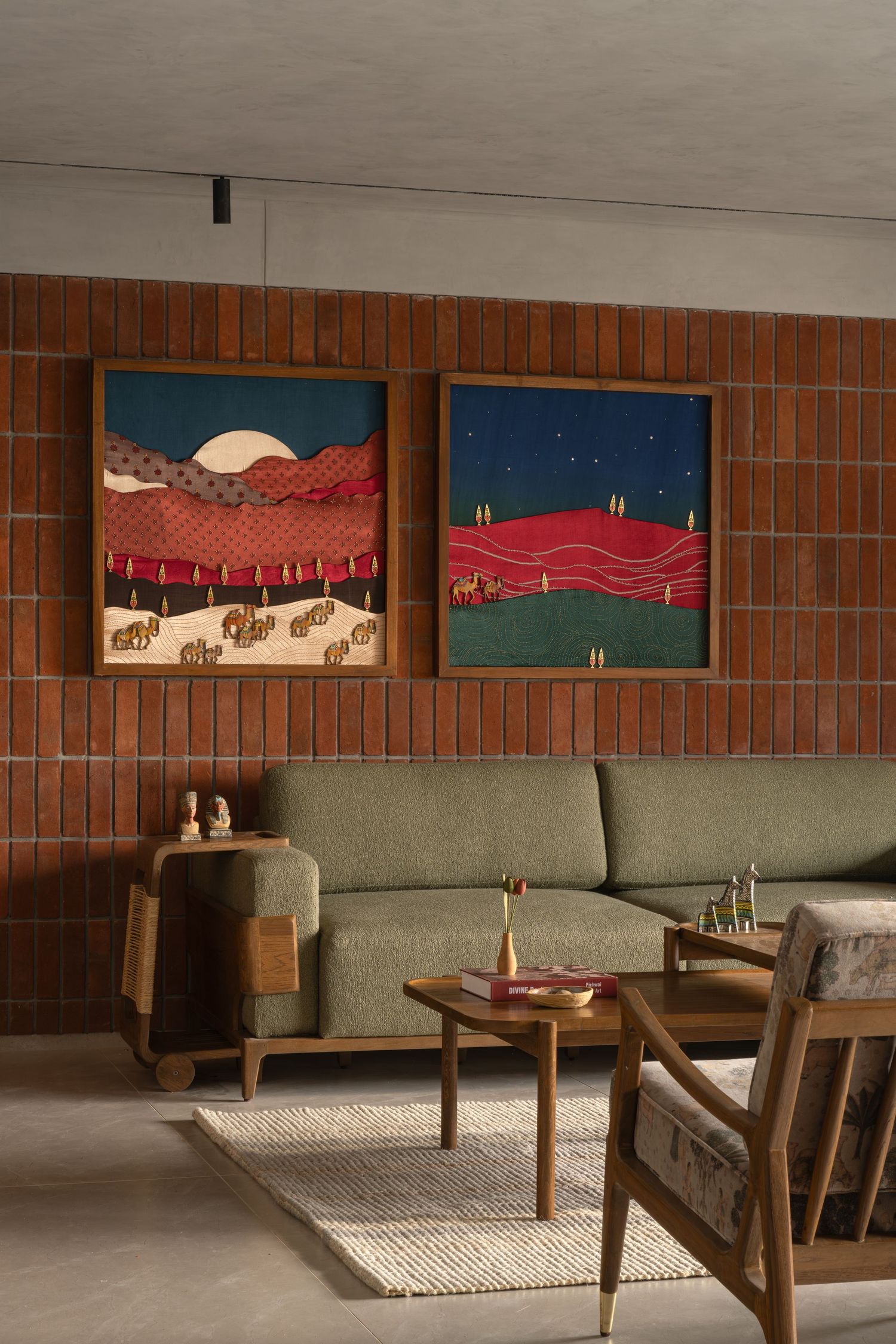 Retro living room with green sectional sofa, wood furniture, red brick wall, and two vibrant landscape artworks.
