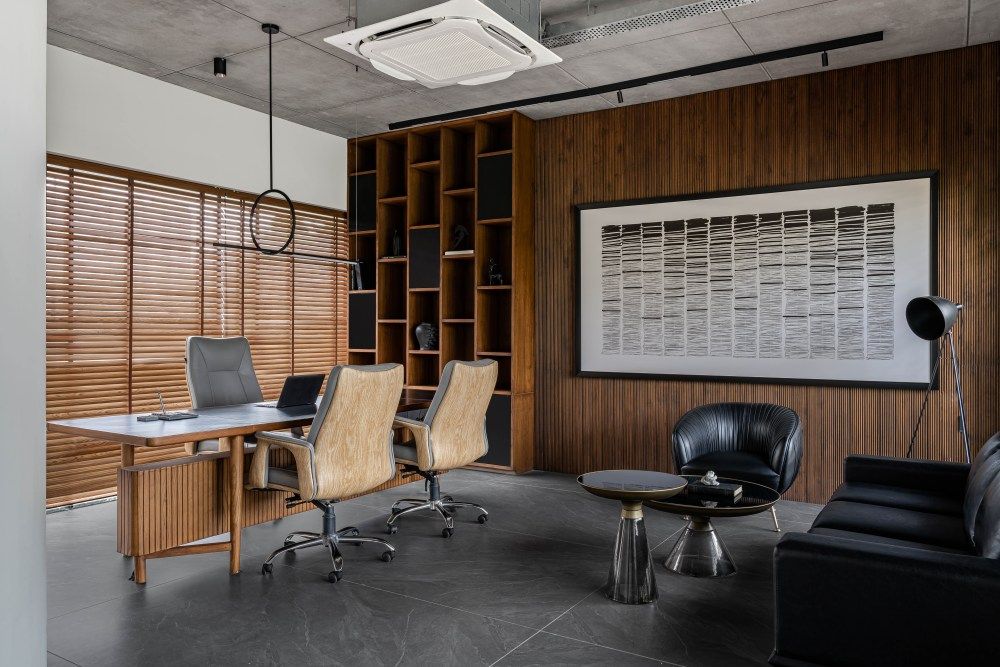 Executive office with dark wood paneling, built-in shelves, wooden blinds, leather chairs, and abstract wall art.