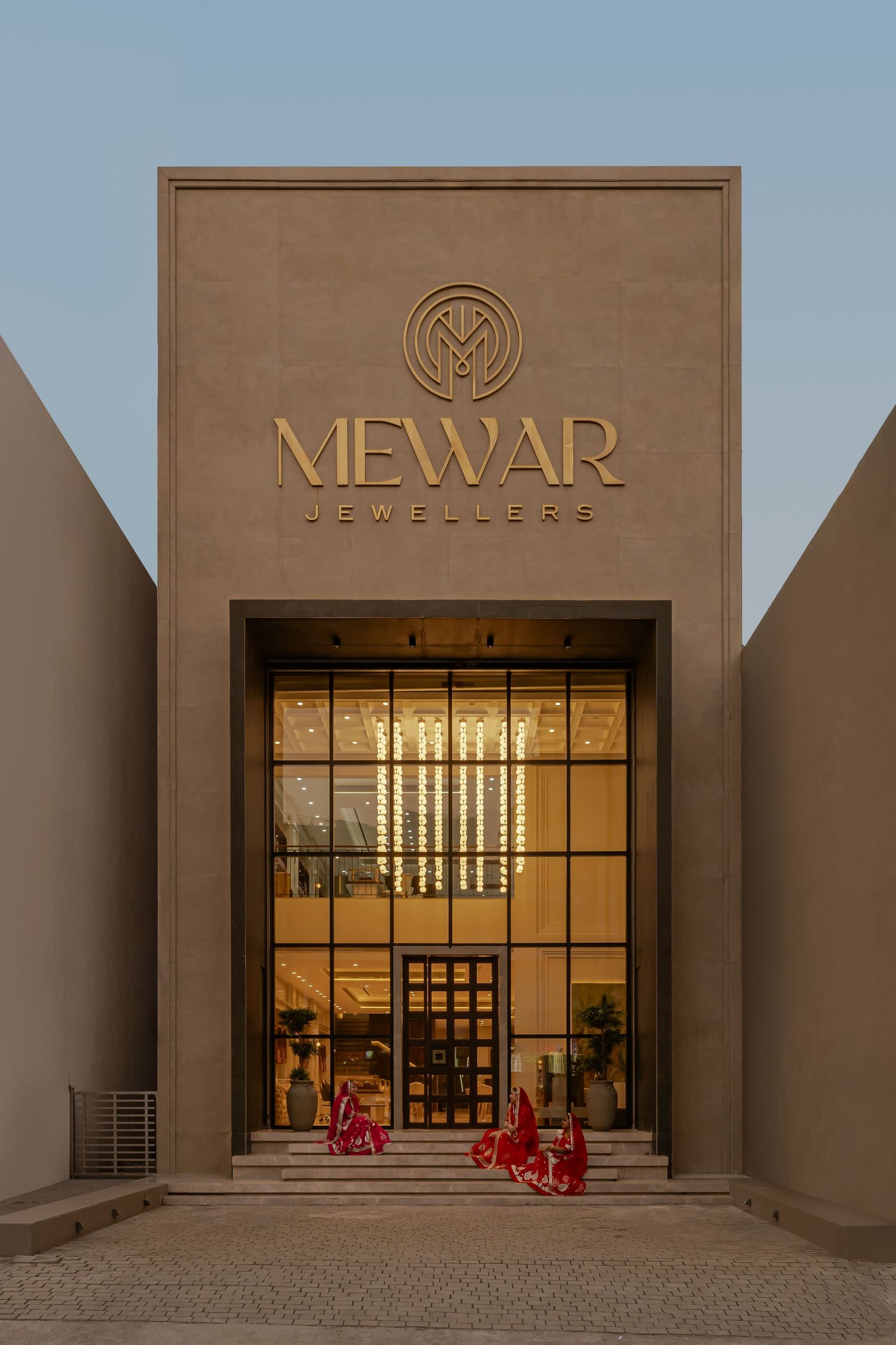 Mewar Jewellers luxury store facade featuring bold gold signage, geometric architecture, and glass entrance at twilight.