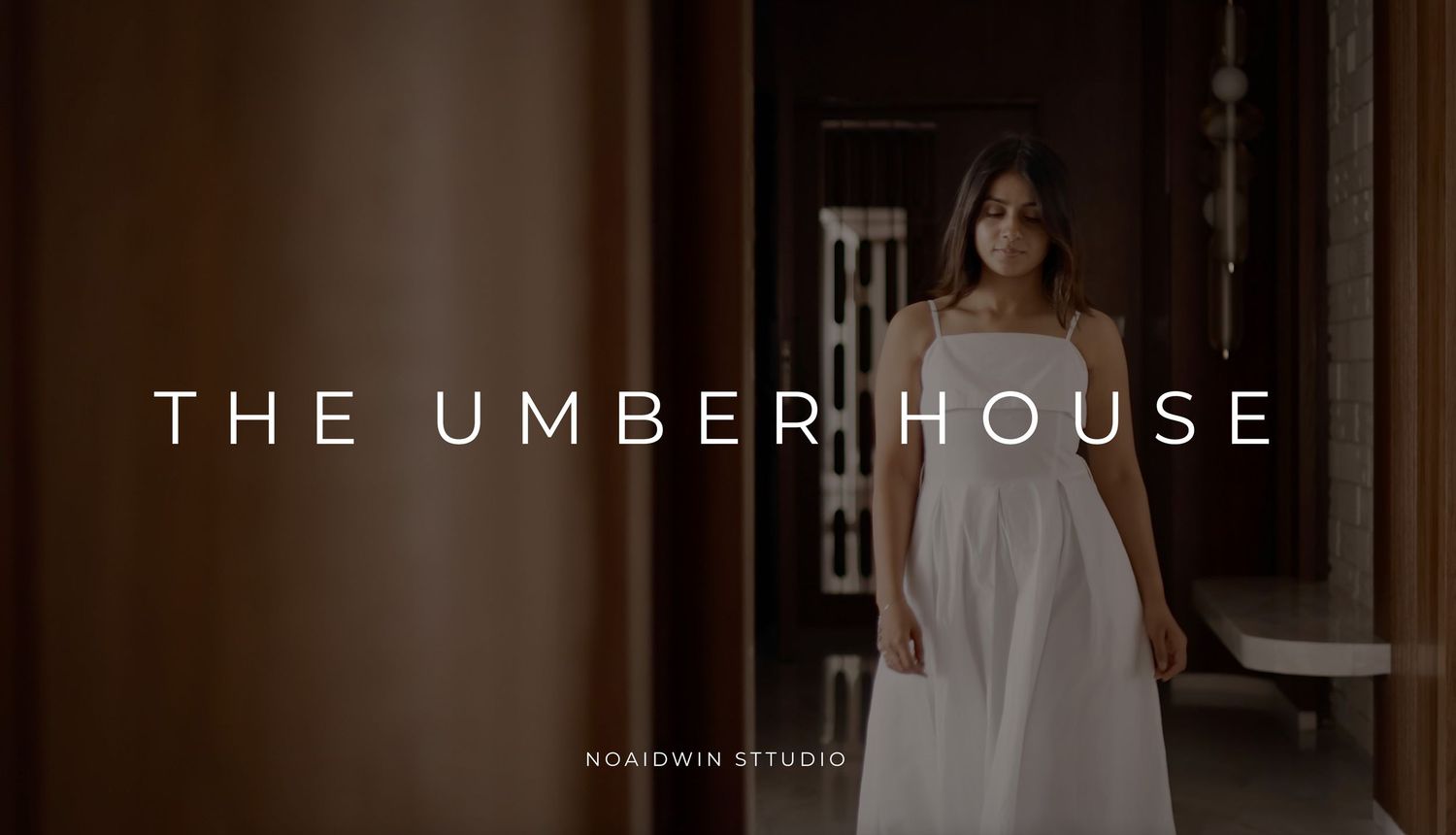 A woman in a white dress stands in a warmly lit hallway with text reading The Umber House by Noaidwin Studio.