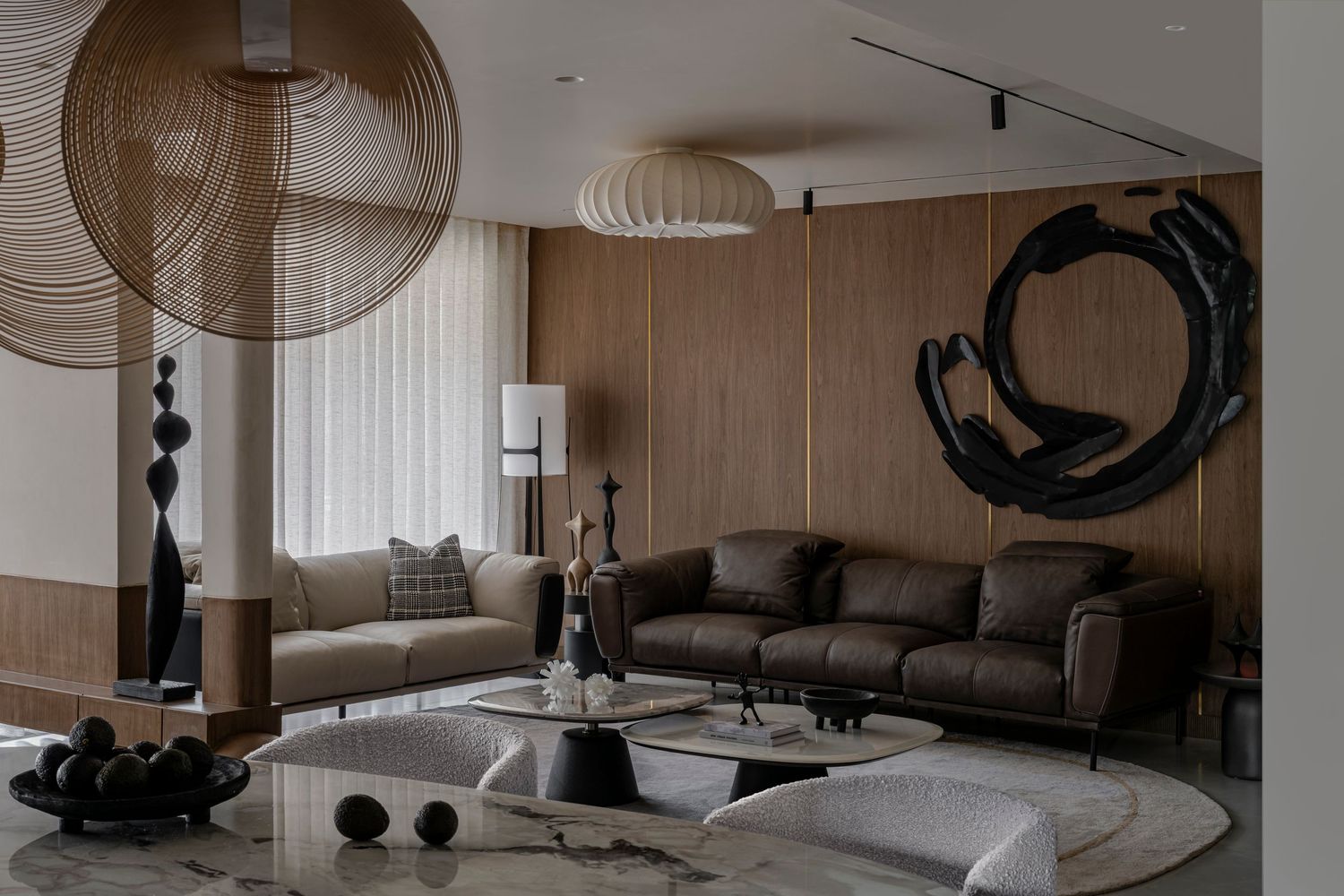 Elegant living room featuring brown leather sofas, woven pendant light, circular black wall sculpture, and sheer curtains.