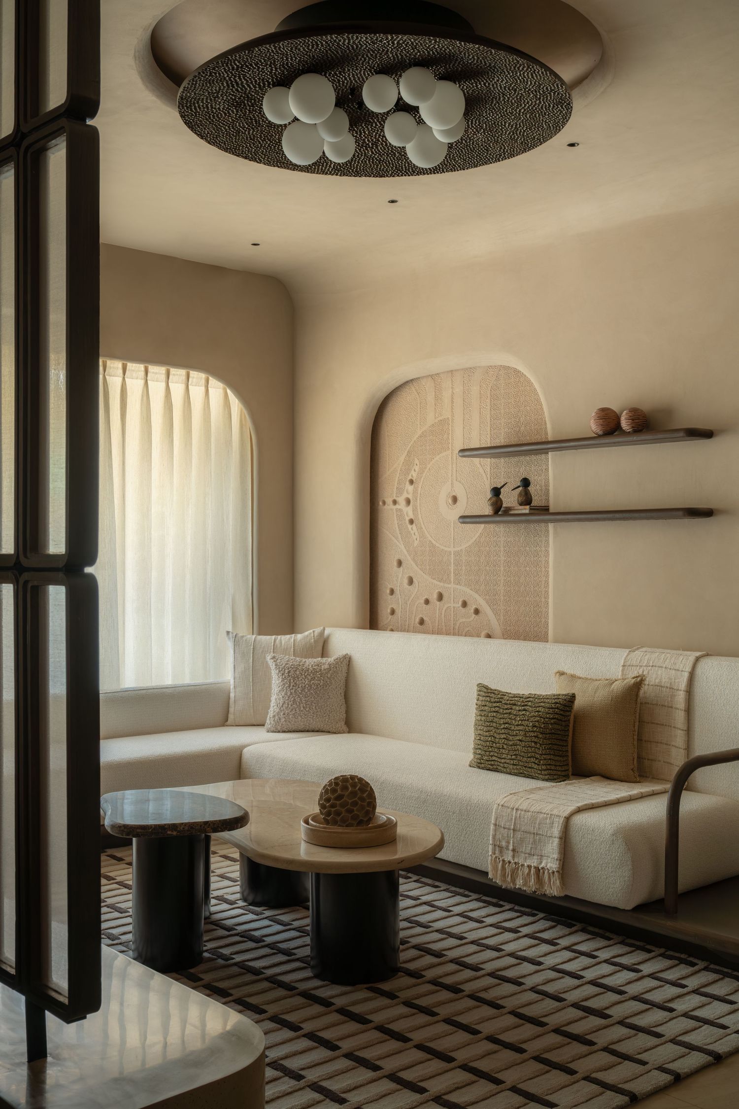 Warm minimalist living room with arched niche, bouclé sofa, globe ceiling fixture, and geometric area rug.