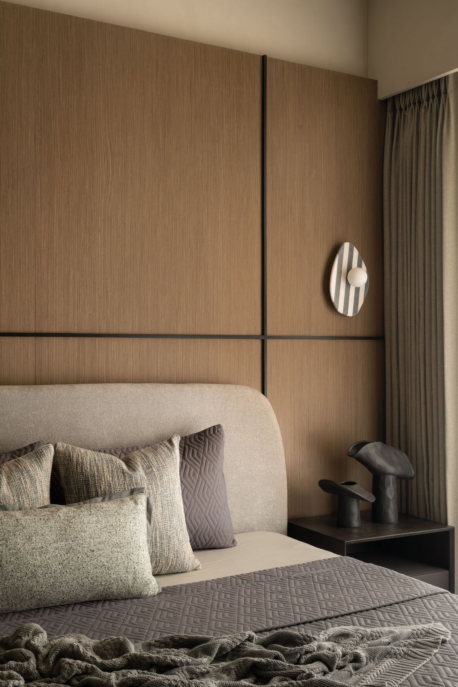 Luxury bedroom with textured wood panel headboard wall, neutral bedding, and sculptural decor accents.