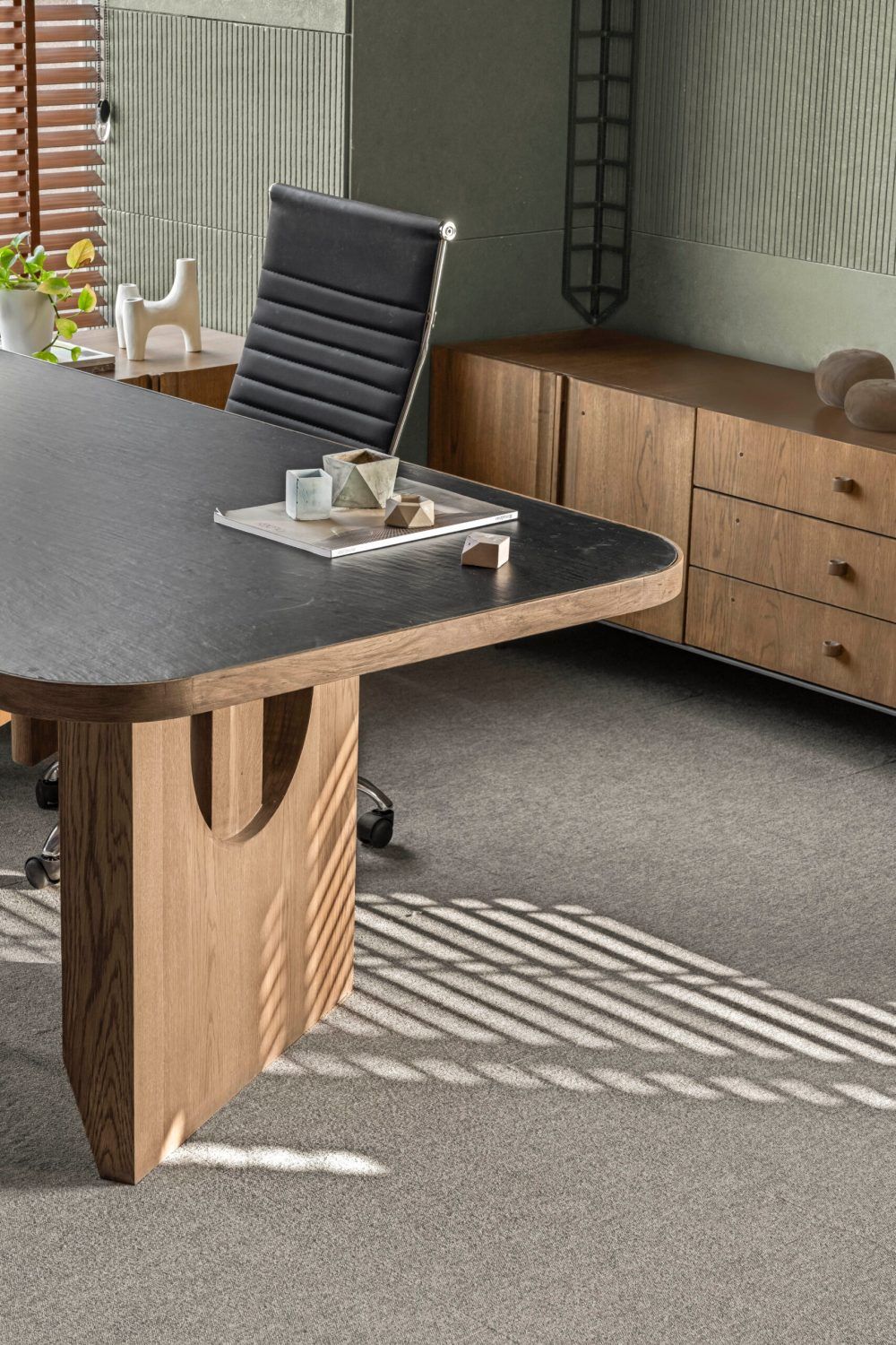 Executive desk with dark stone top, wooden base, leather chair, and wooden credenza.