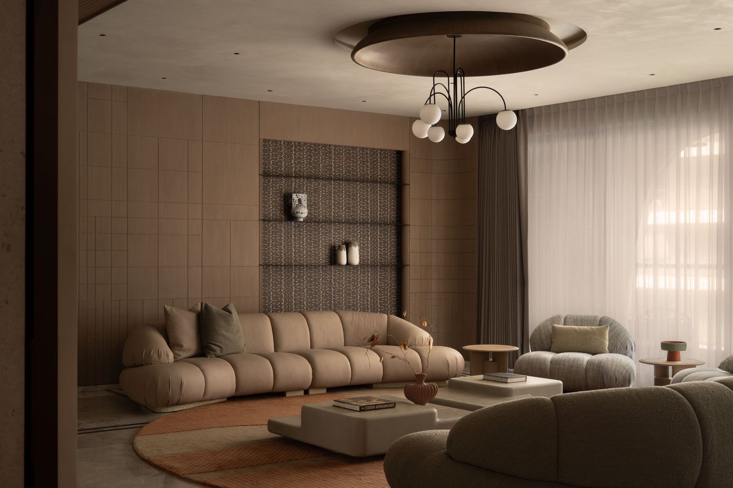 Modern living room with beige modular sofa, round rug, built-in shelving, and elegant globe chandelier in warm neutral tones.