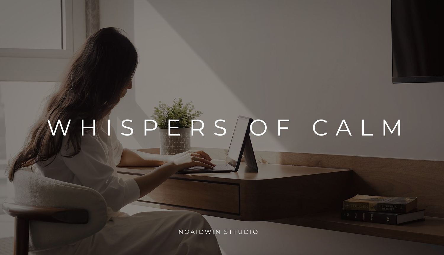 Woman sitting at a wooden desk working on a tablet in a minimalist sunlit room, overlaid with text Whispers of Calm.