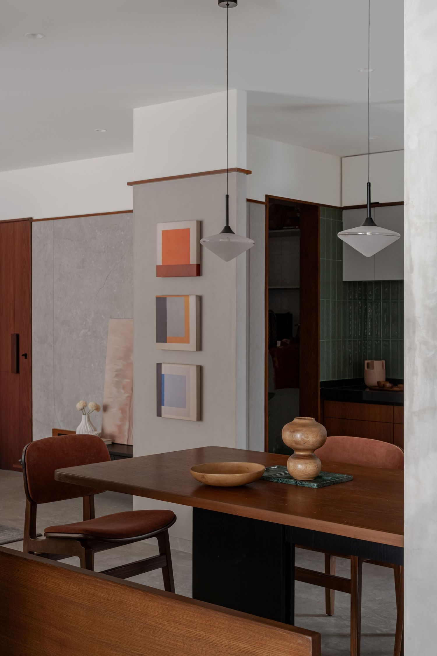 Modern dining area with walnut table, pendant lights, colorful geometric wall art, and warm wood accents.