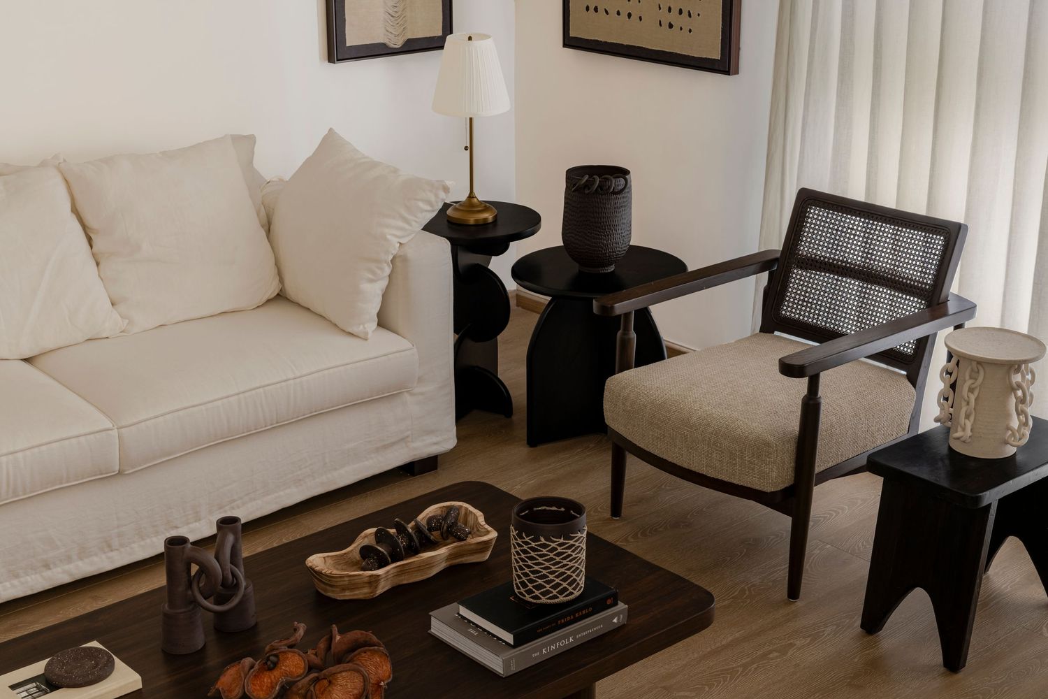 Cozy living room with white sofa, rattan chair, dark wood coffee table, and woven decor.