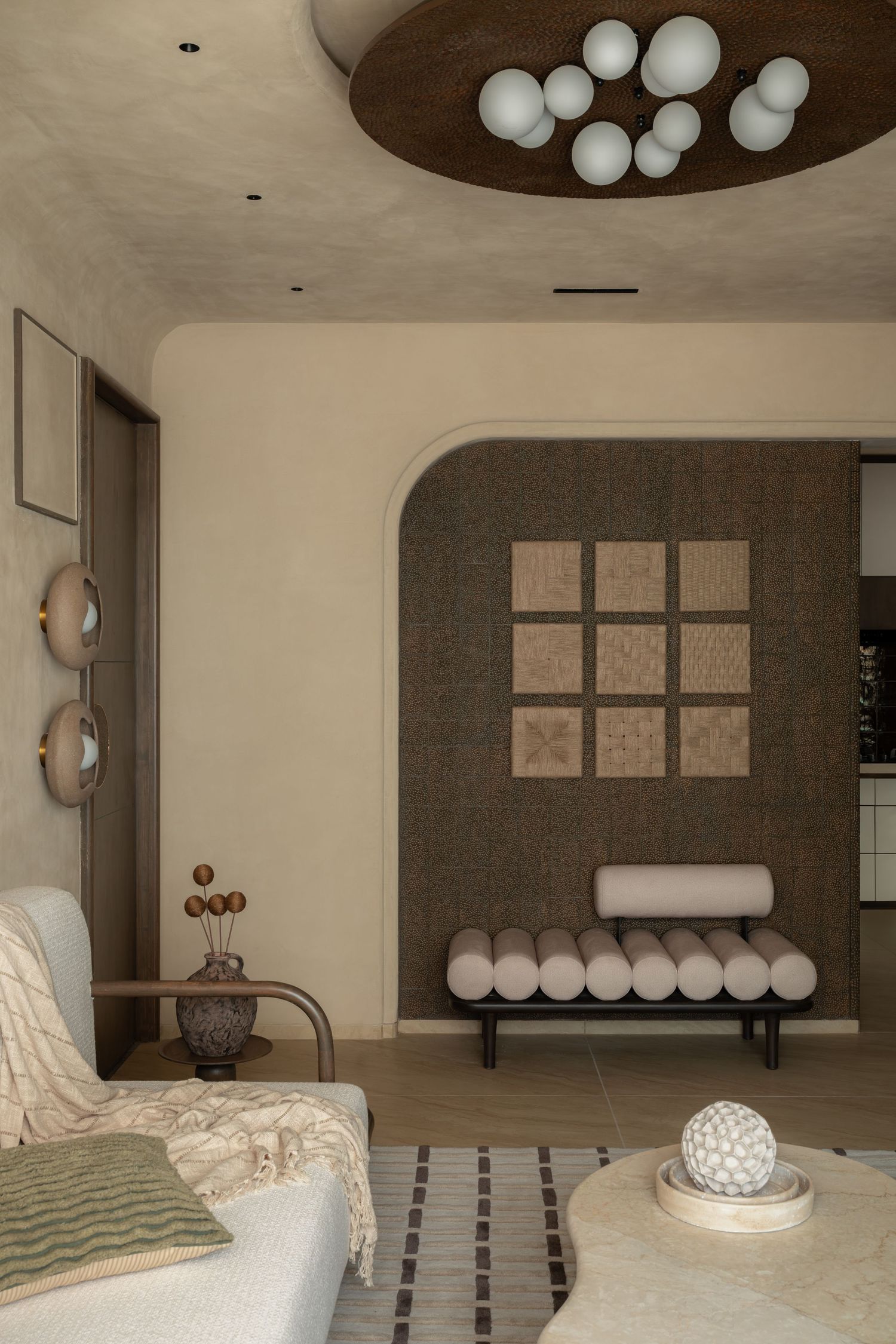 Modern living room with arched alcove, globe chandelier, roll cushion daybed, and neutral beige tones.