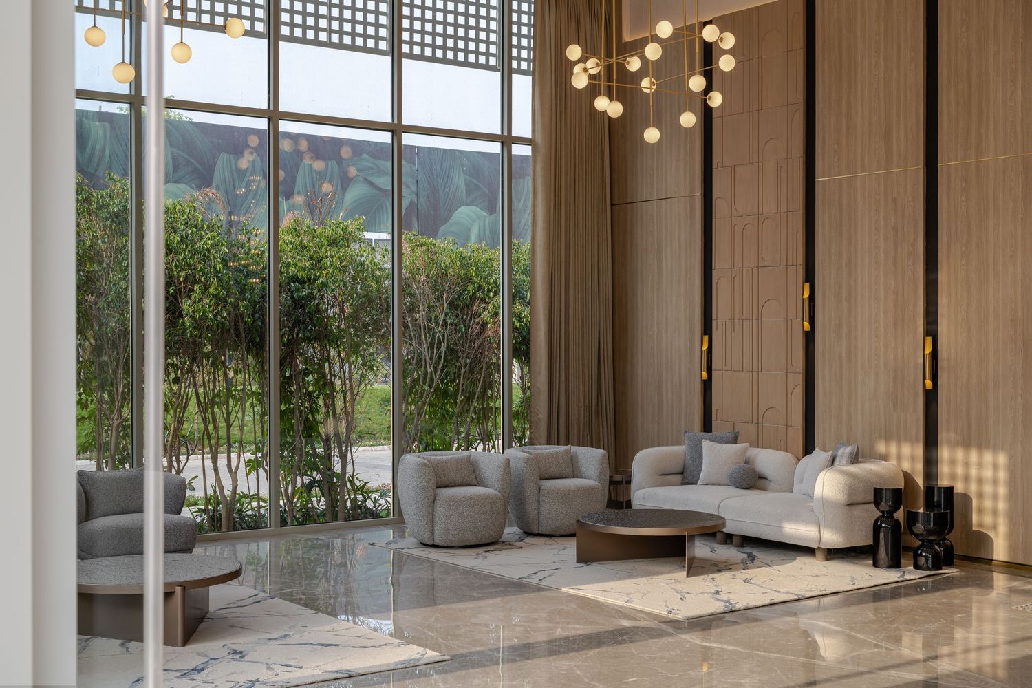 Luxurious lobby with marble floors, floor-to-ceiling windows, globe chandelier, and gray seating.