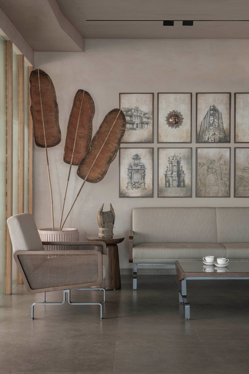 Warm neutral lounge featuring oversized dried banana leaves, gallery wall sketches, and modern furniture.